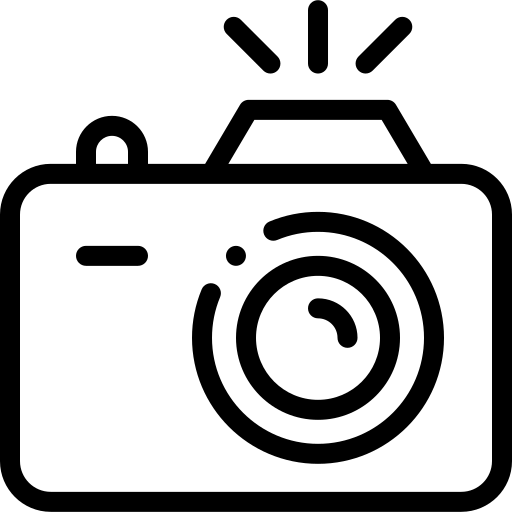 Black and white icon of a camera with flash rays, featuring a circular lens and minimalist outline design.