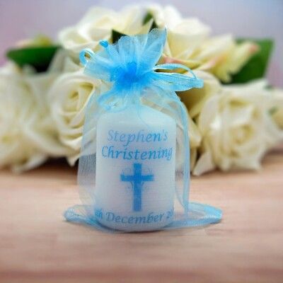 White roses and blue baptism favor bags with cross designs create an elegant religious celebration display.