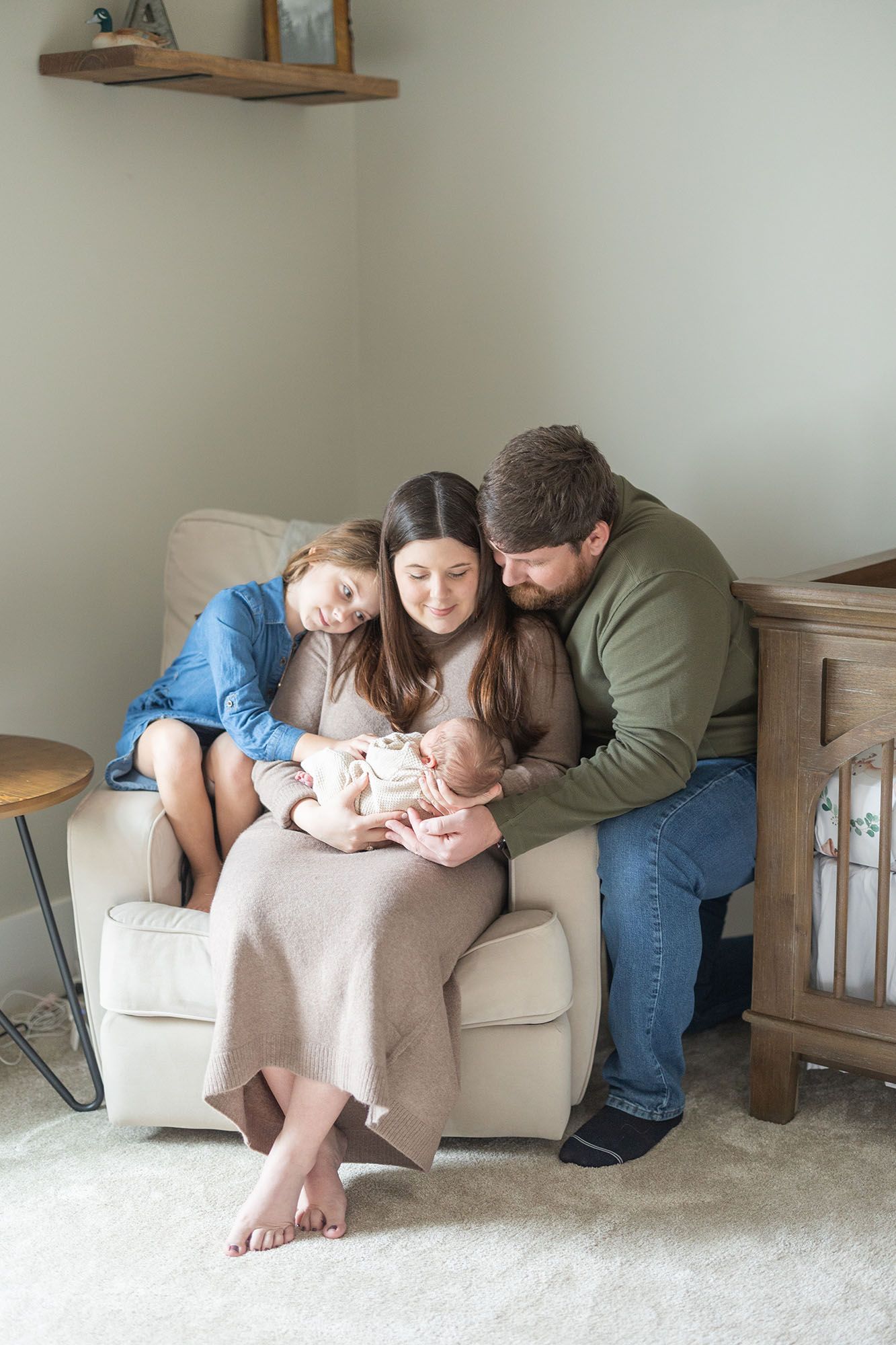 Family snuggled up in a nursery looking at a baby boy by Alex Ishee Photography.