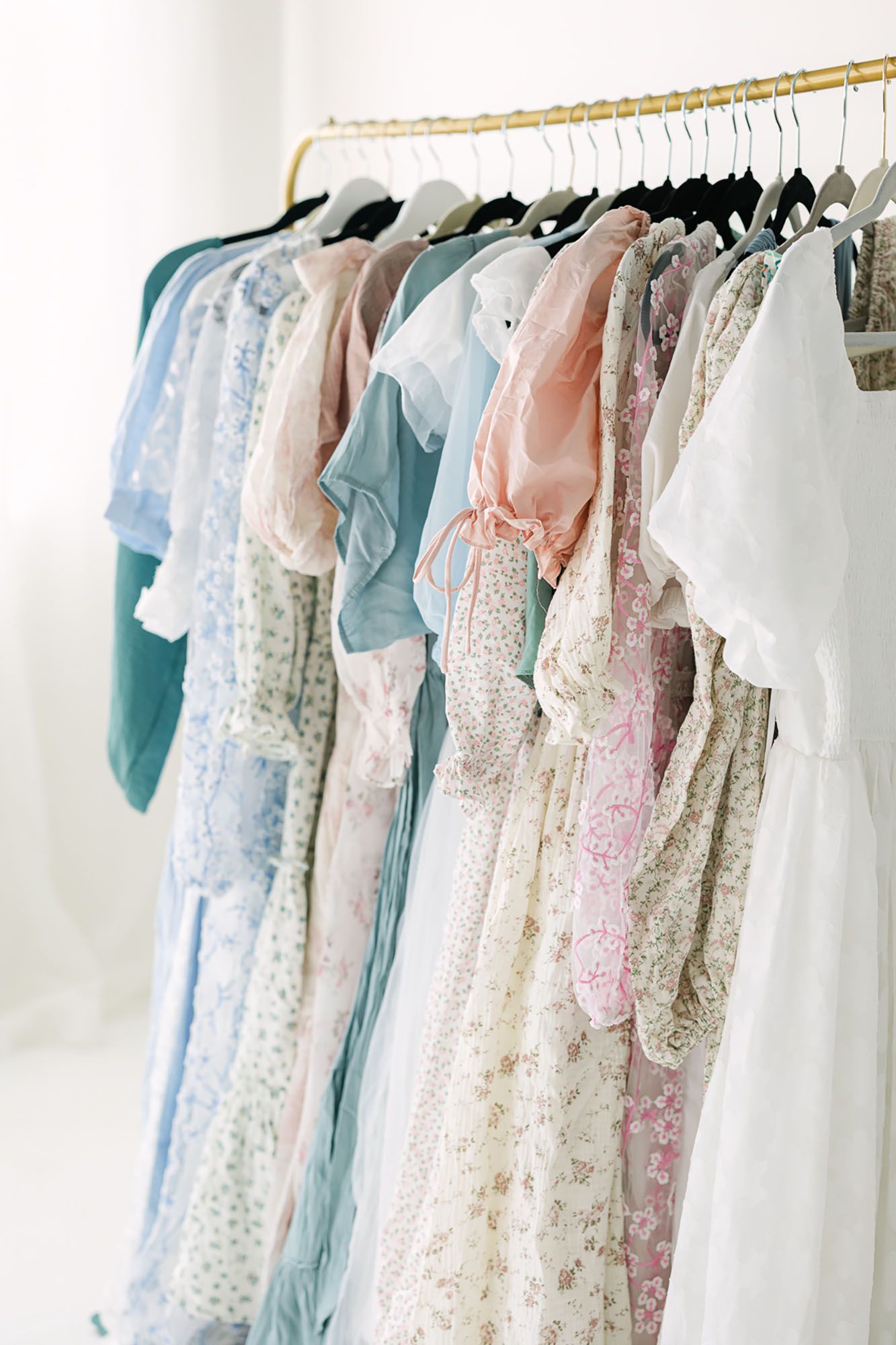 Alex Ishee Photography client closet full of flowy dresses with soft pinks, blues, and white fabrics.