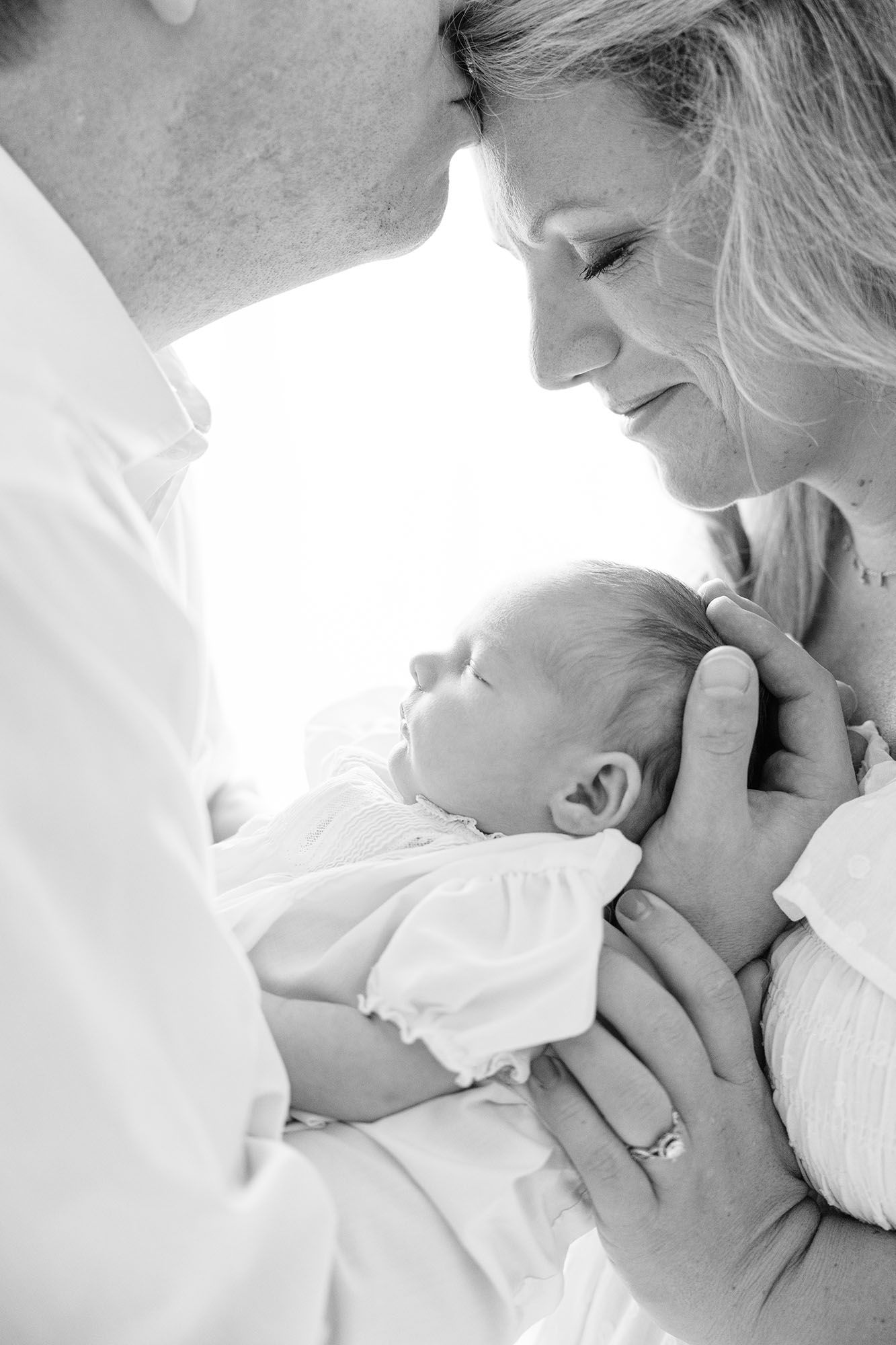 Black and white photo of mom, dad, and baby side profiles in front of a window by Alex Ishee Photography.