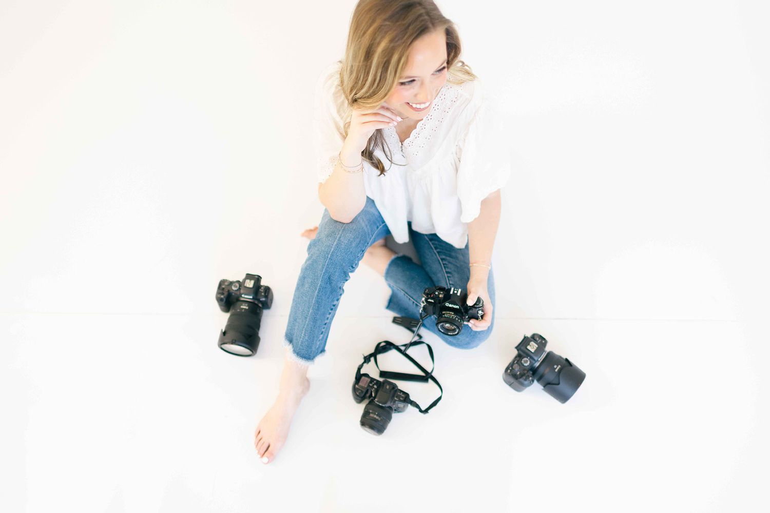 Fairhope photographer, Alex Ishee, sitting on the floor next to cameras used to capture families, newborns, and milestone sessions.