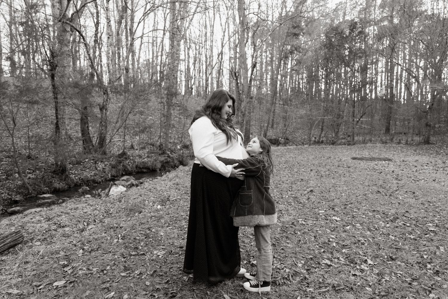 Vintage black and white photograph of two people standing in a wooded clearing in winter.
