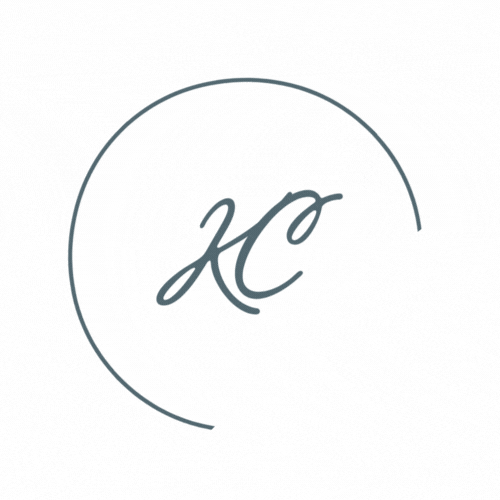 A minimalist gray circular logo design featuring cursive letters 'KC' within a thin circular border.