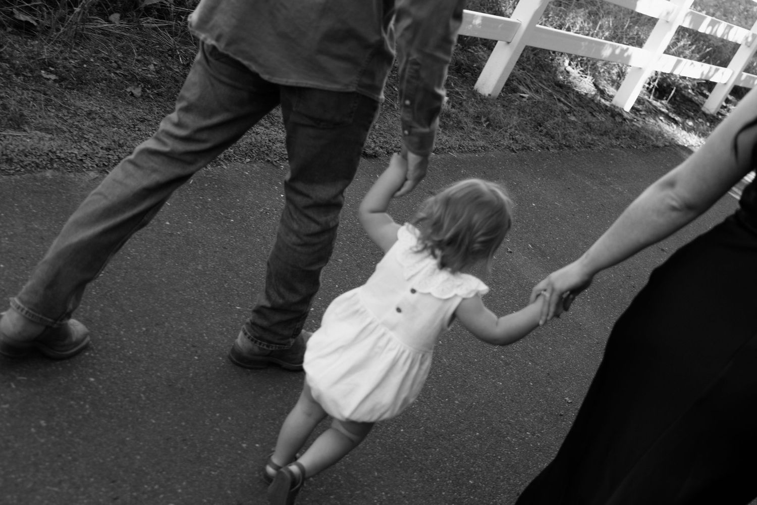 People's legs and feet shown in black and white while dancing or moving on a dance floor or paved surface.