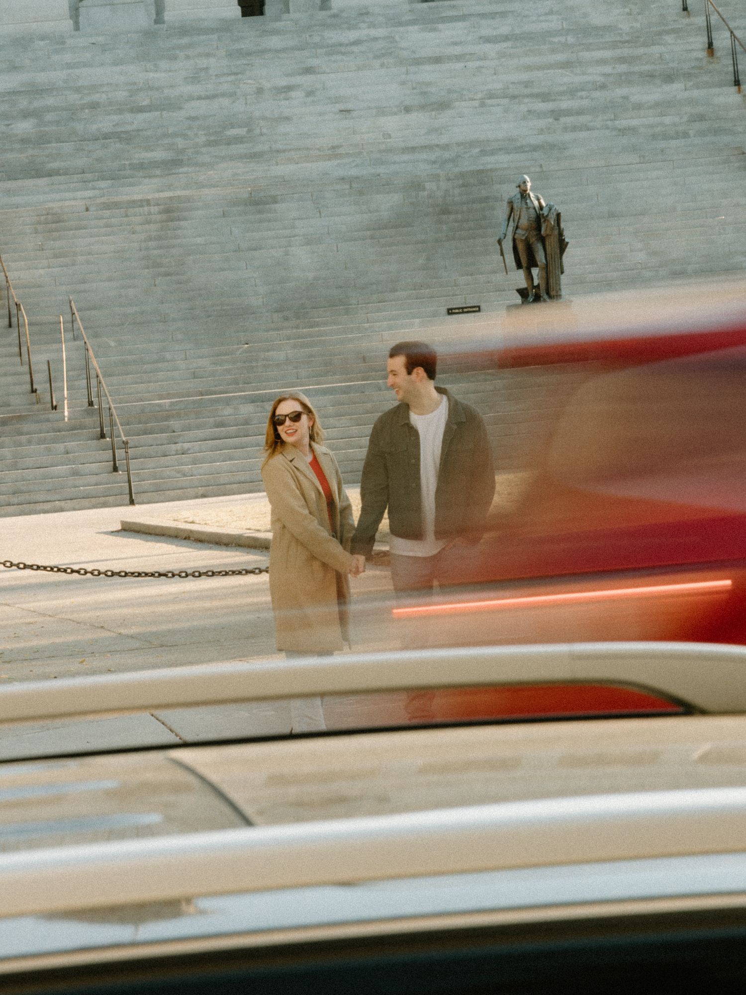 Two people stand near a long red stripe on a gray floor with shadows cast in series of action-like poses.