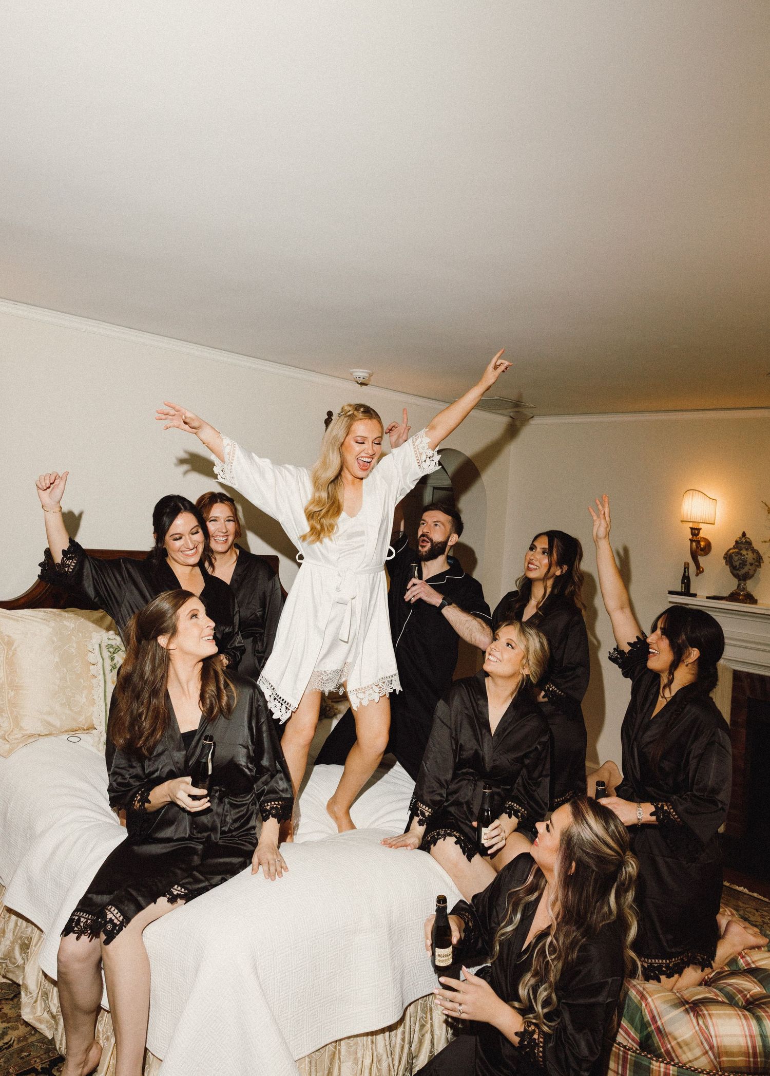 A group of friends in black and white outfits jumping and celebrating together during a party indoors.