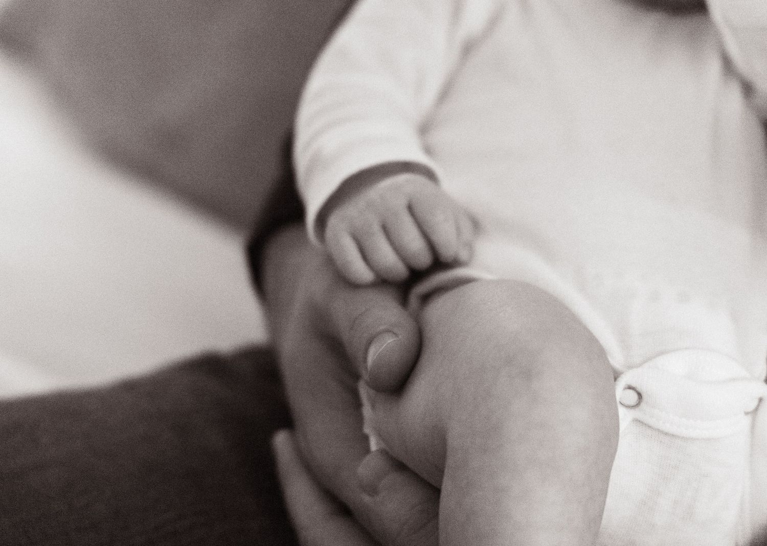 Close-up black and white image of baby's hand resting gently.