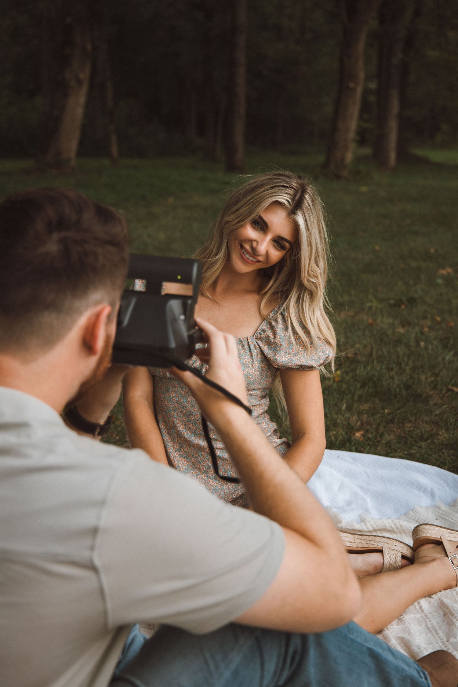 Photography session in woodland setting with couple on white blanket.