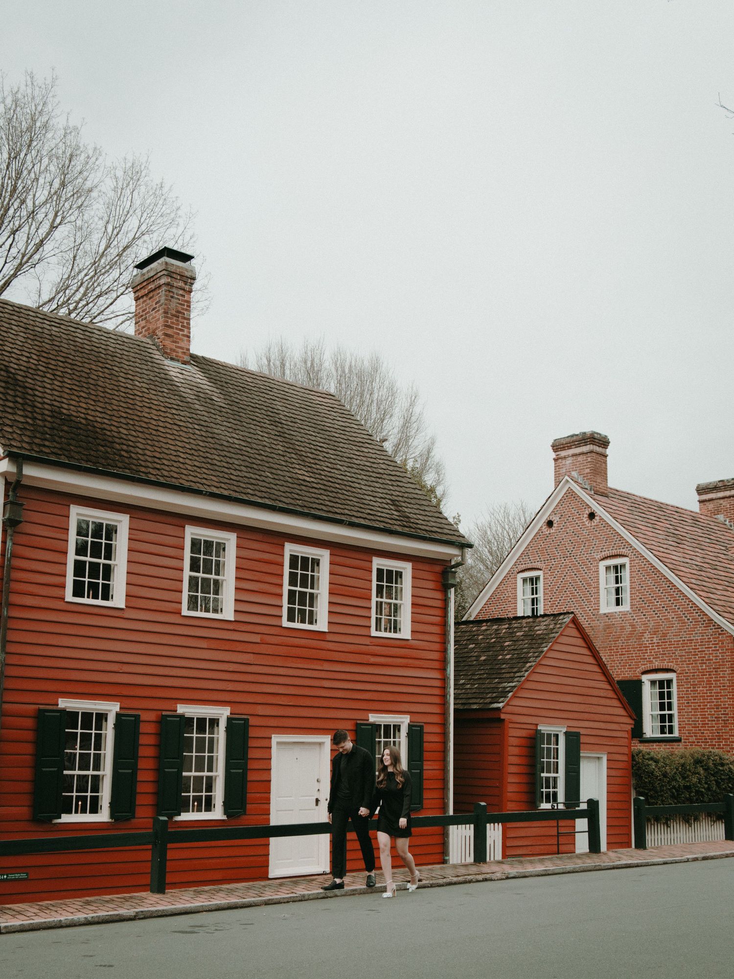 Historic red colonial buildings with white trim windows and brick chimneys along a street.