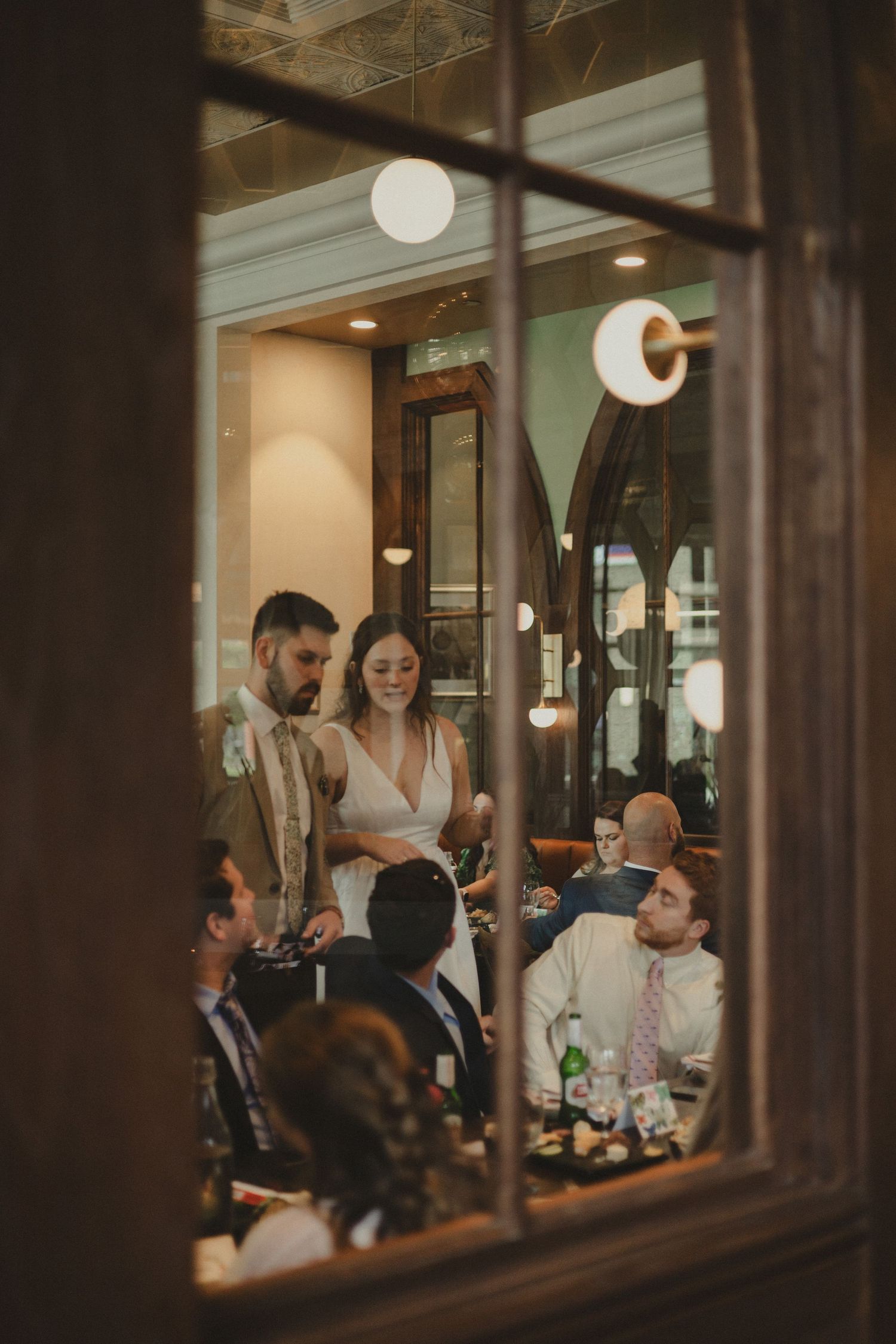 View through a window of a restaurant gathering with warm lighting.