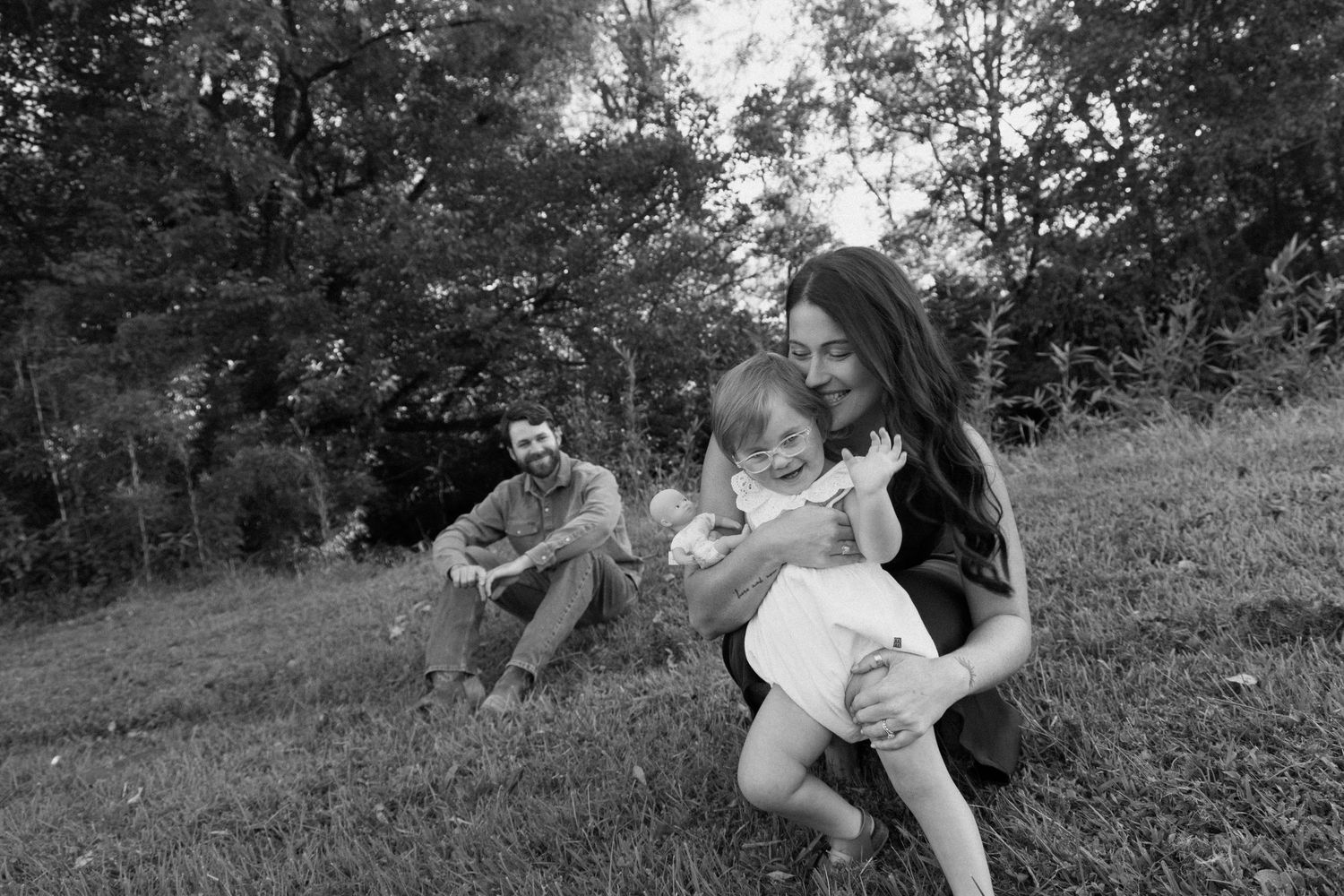 A black and white photograph shows people relaxing outdoors on a grassy hillside on a summer day.