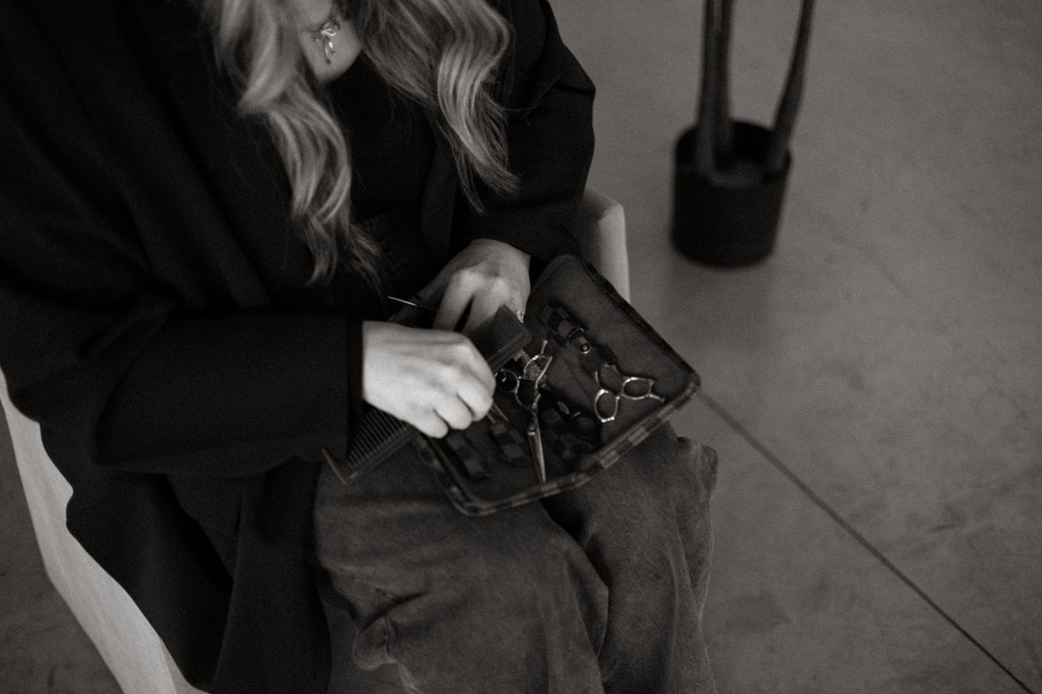 A person in a black sweater sews with a needle and thread in a black and white photograph.