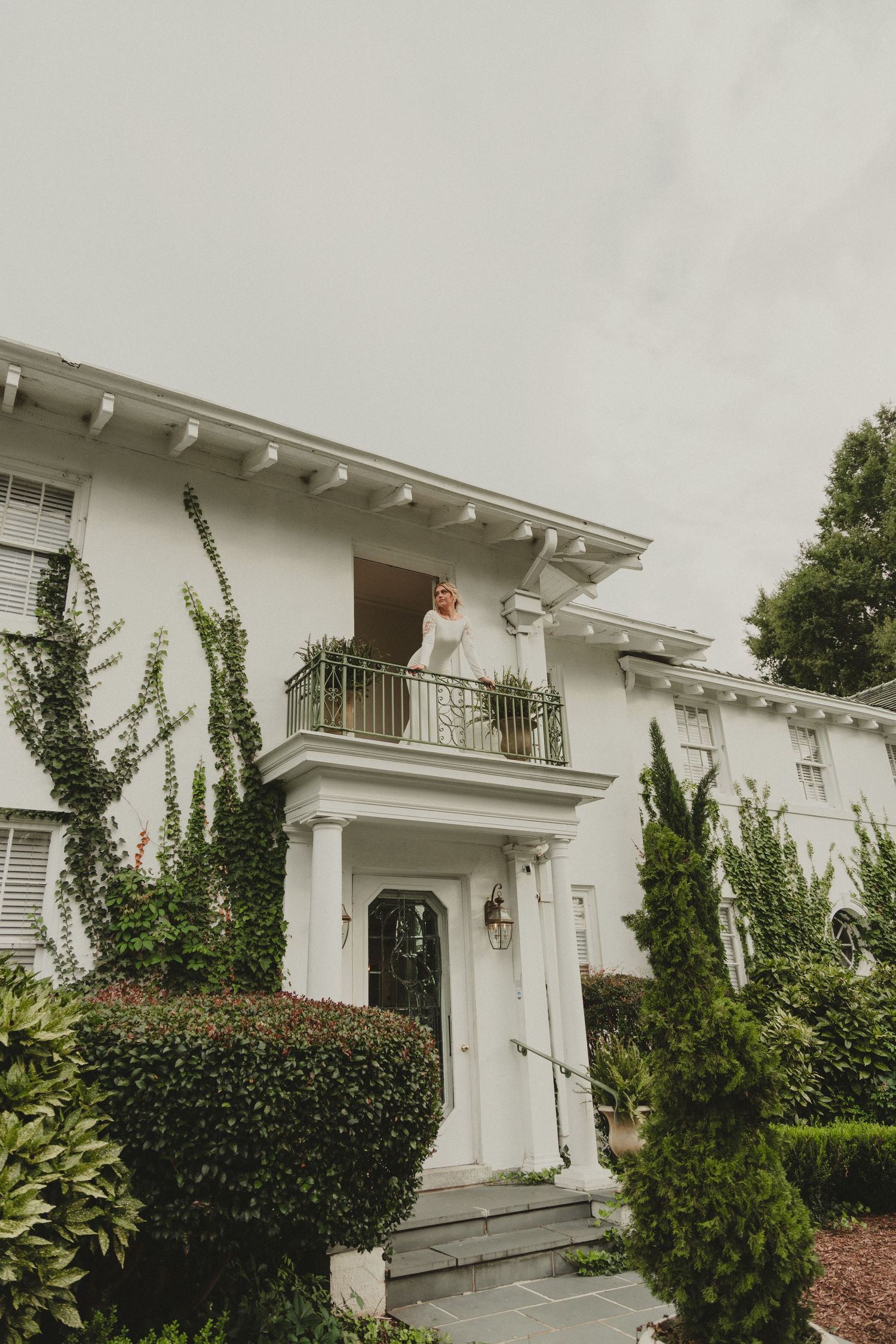 White colonial-style exterior of a residential building with ornate columns and balcony features.