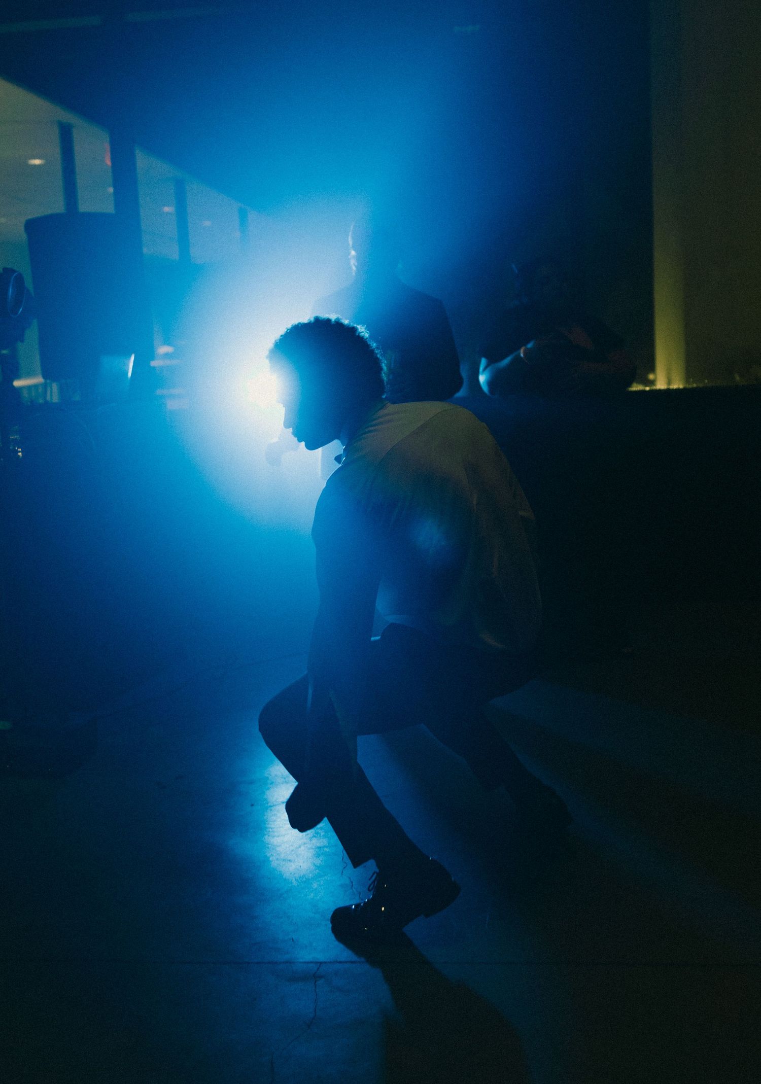 Silhouette of a person diving underwater in dark blue water with dramatic backlighting creating a moody atmosphere.