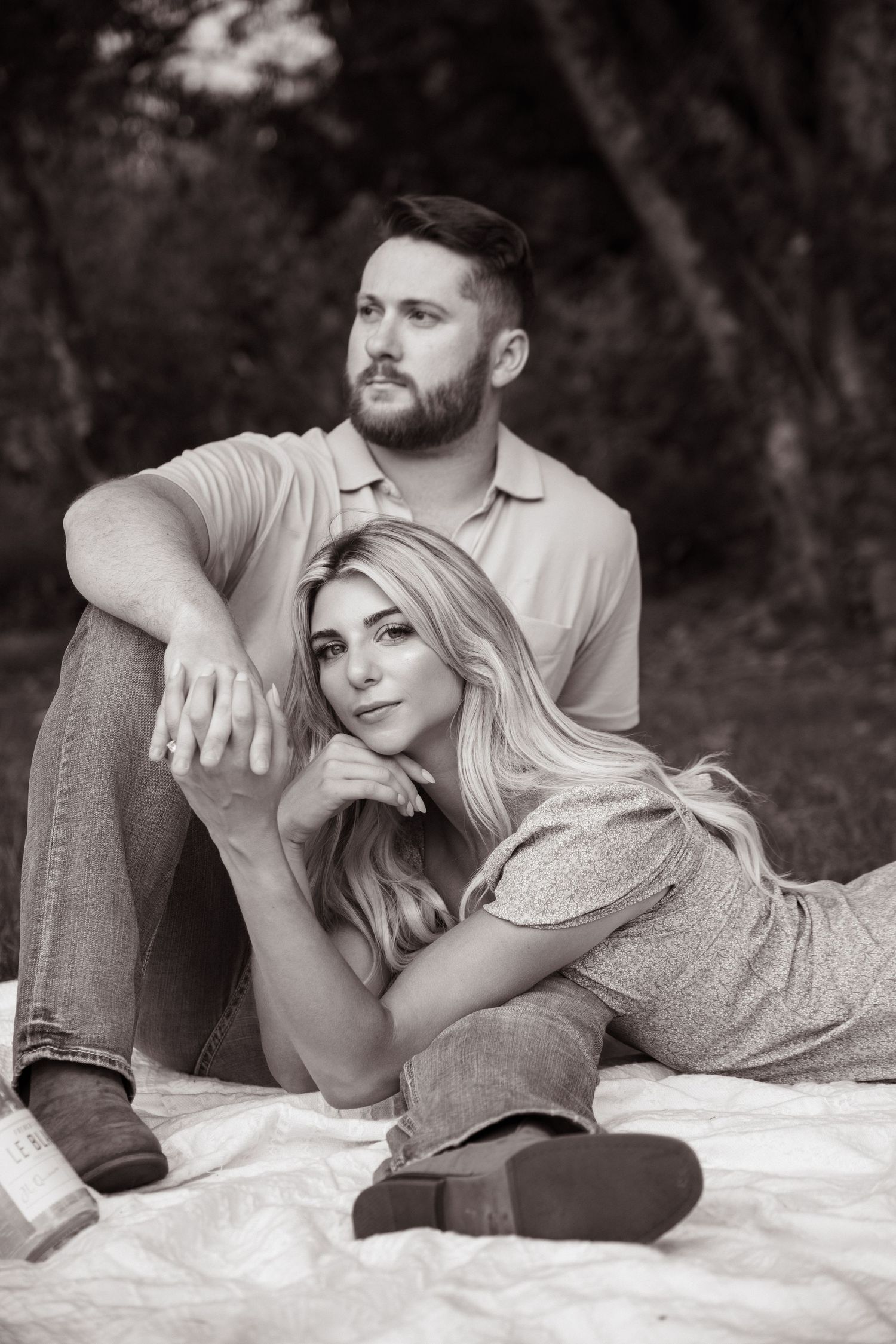 Black and white portrait of couple relaxing on blanket in romantic pose.