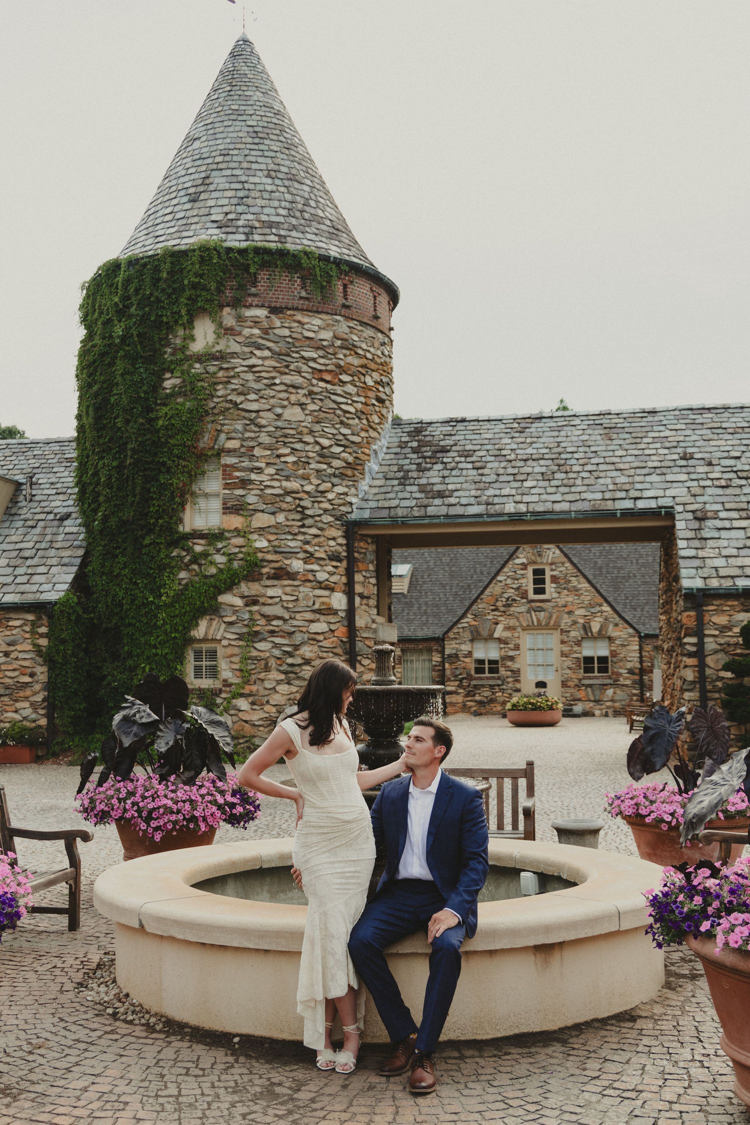 Romantic proposal scene at a stone castle with ivy and pink flowers.