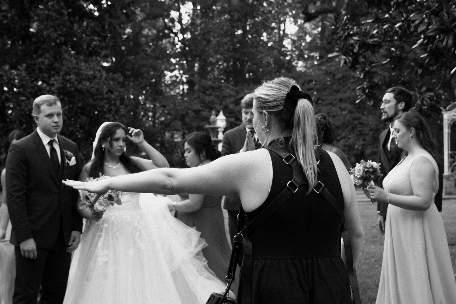 Wedding guests celebrate and dance together during an outdoor garden reception in black and white photography.