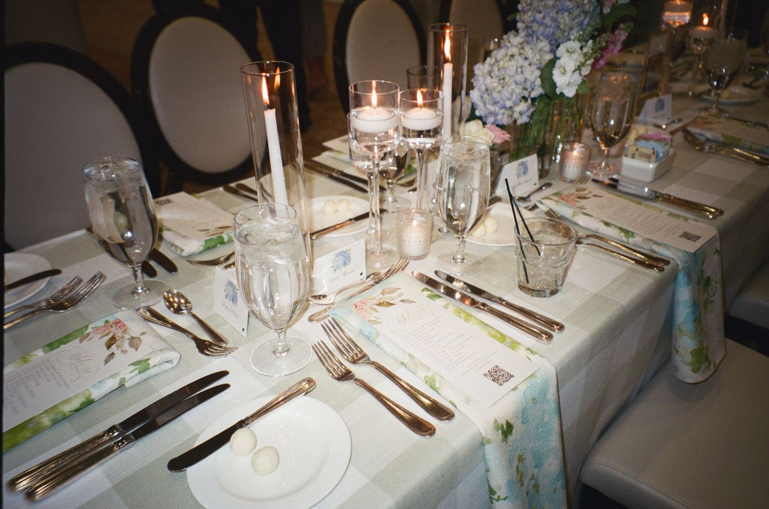 Elegant table setting with white linens, candlesticks, and place settings for a formal wedding reception dinner.