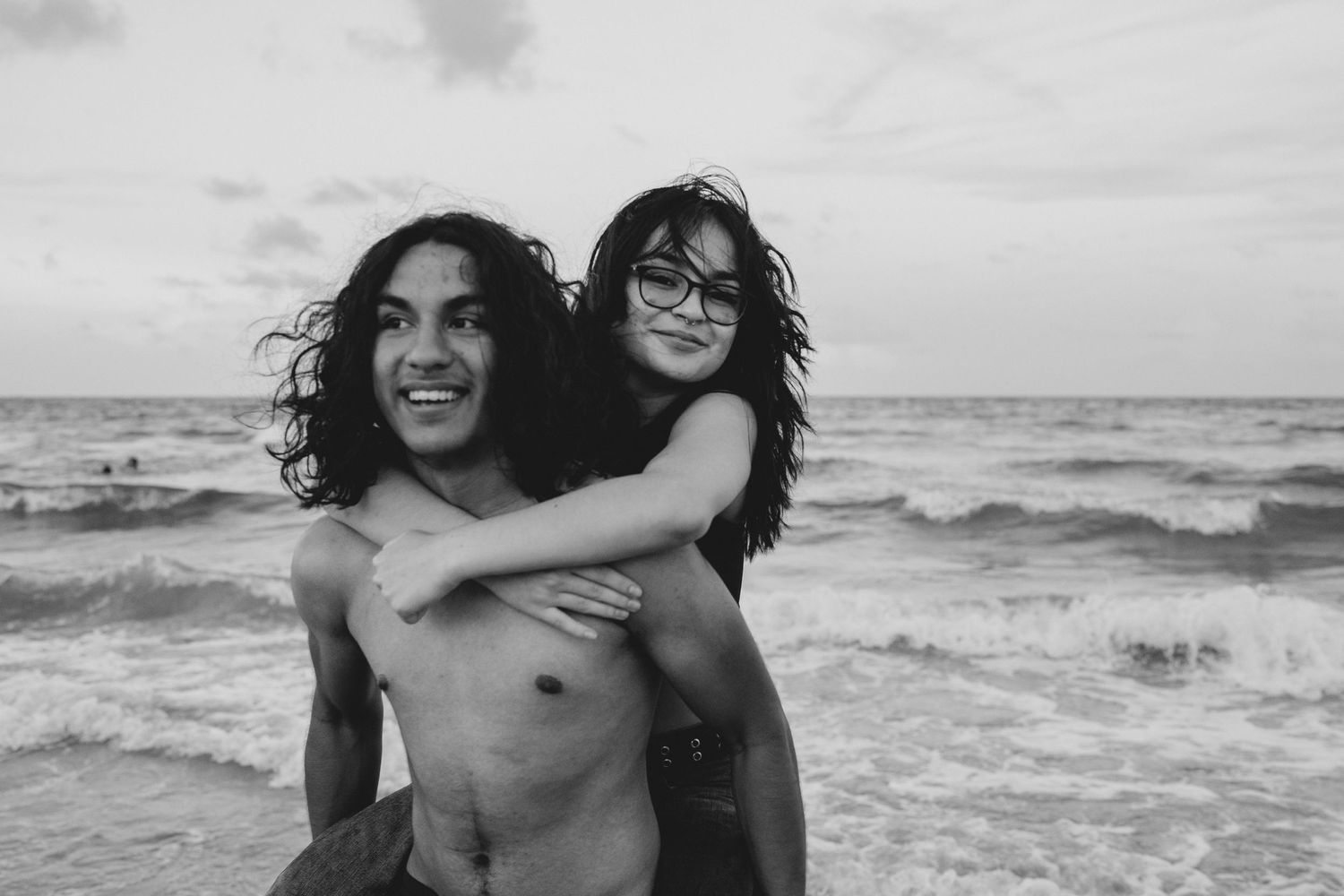 brother giving sister piggyback ride at the beach