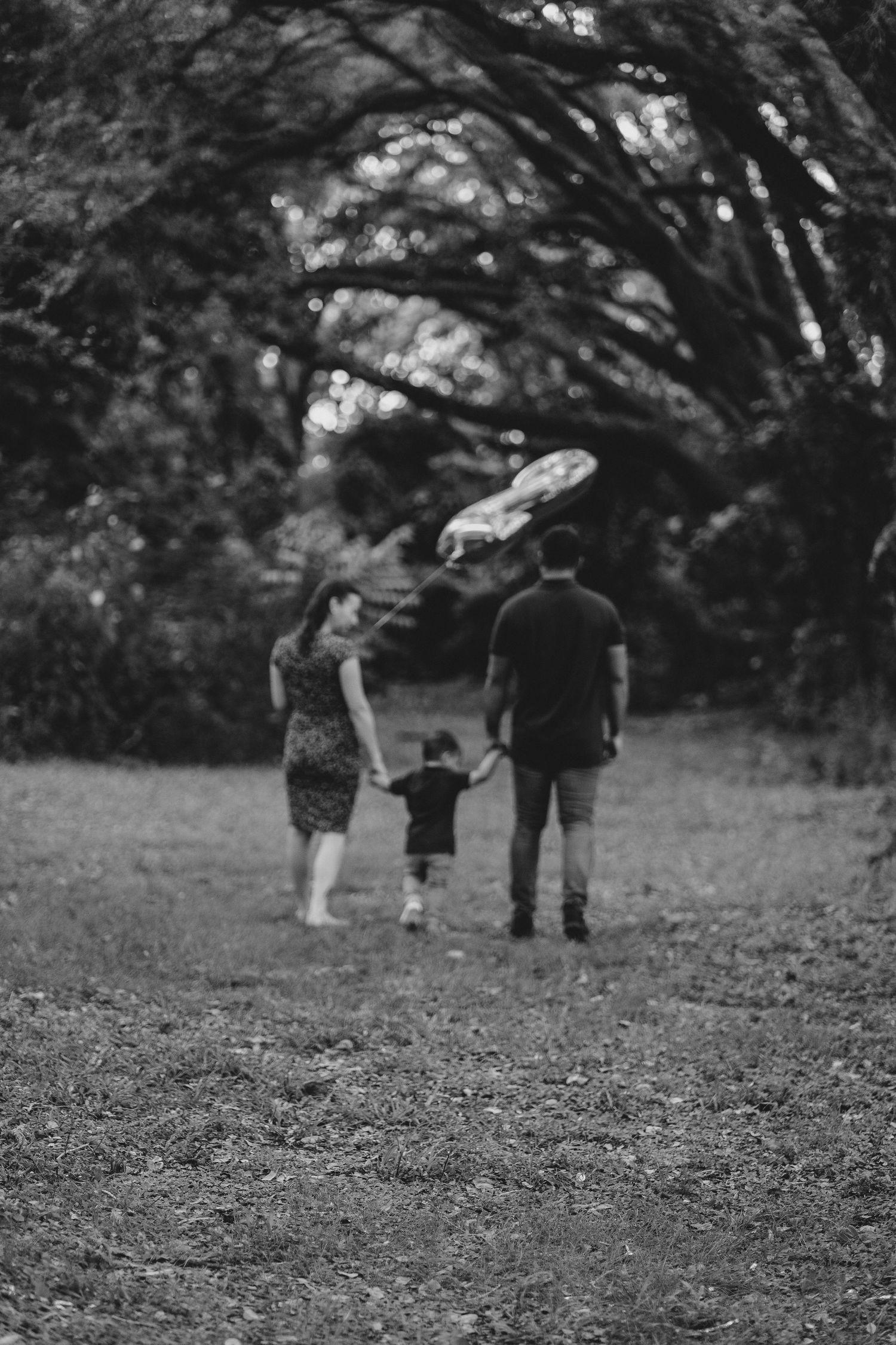 mom and dad holding hands with their son holding a #2 balloon walking away