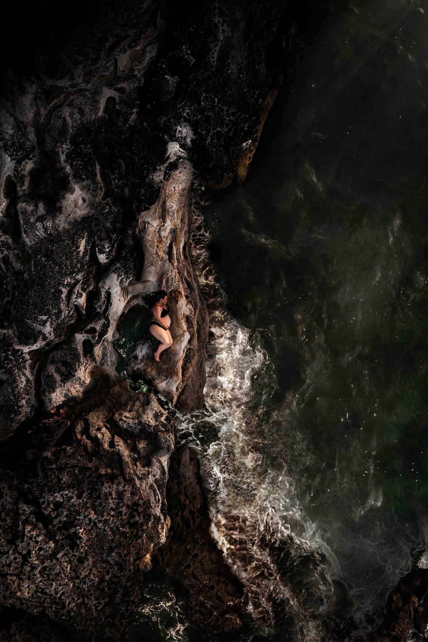Drone Maternity photography Jervis Bay Shoalhaven NSW. Pregnant women laying on textured volcanic rocks. Jervis Bay Maternity Photographer