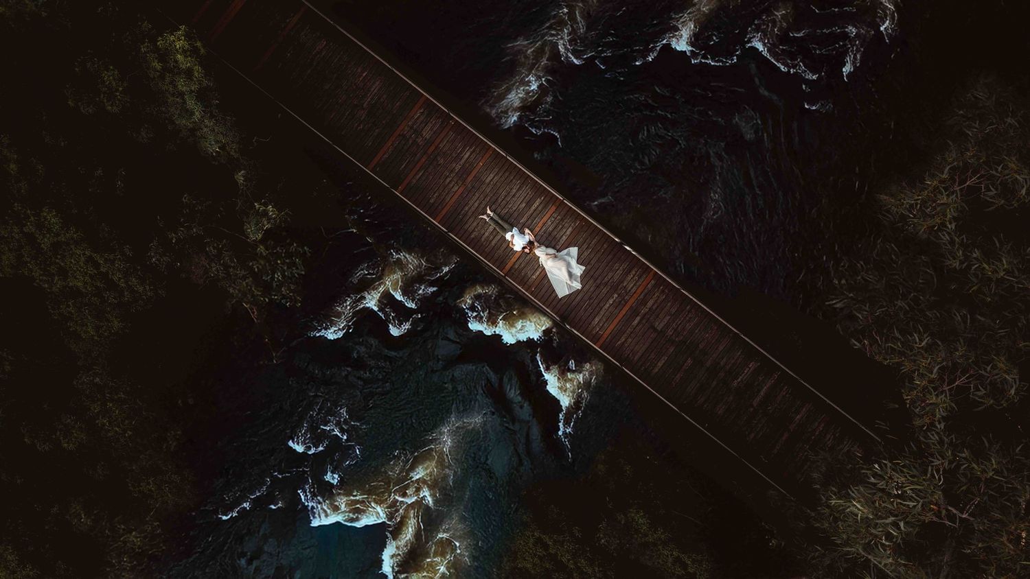 Drone Maternity Photography Jervis Bay & Shoalhaven. Pregnant women & Husband laying on a bridge- Jervis Bay Maternity Photo
