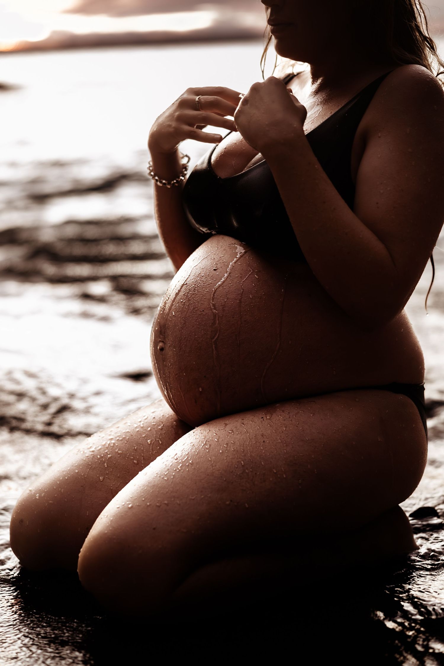 sunset maternity beach portrait. pregnant women in the shallow waters of Jervis Bay, water trickling on her growing belly.