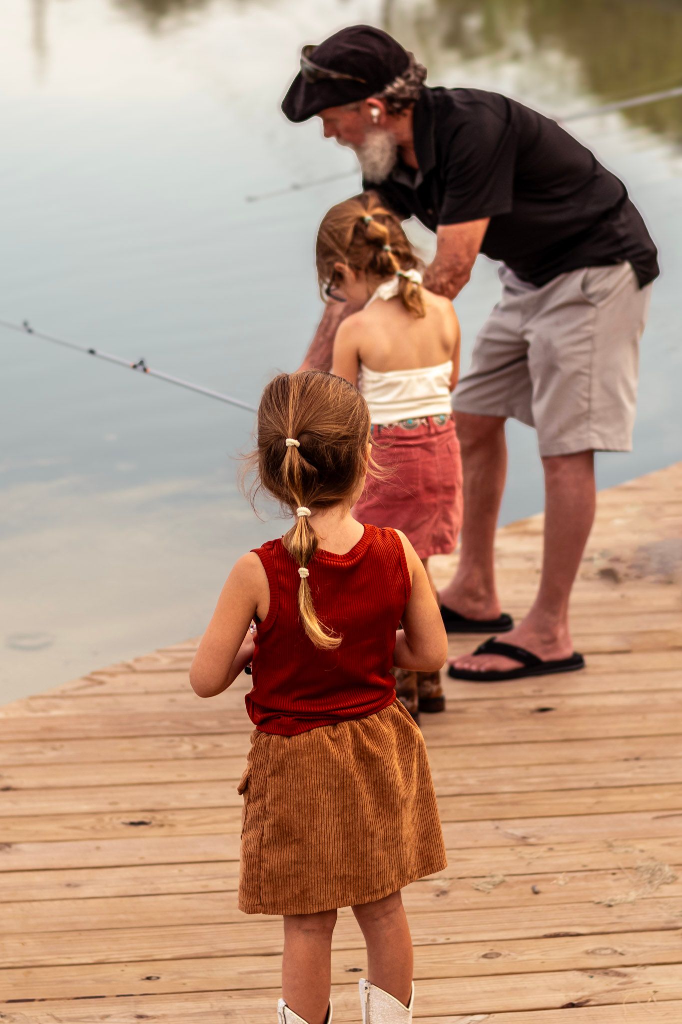 Natural interaction as a grandparent teaches a grandchild how to cast a line, both focused and smiling softly.