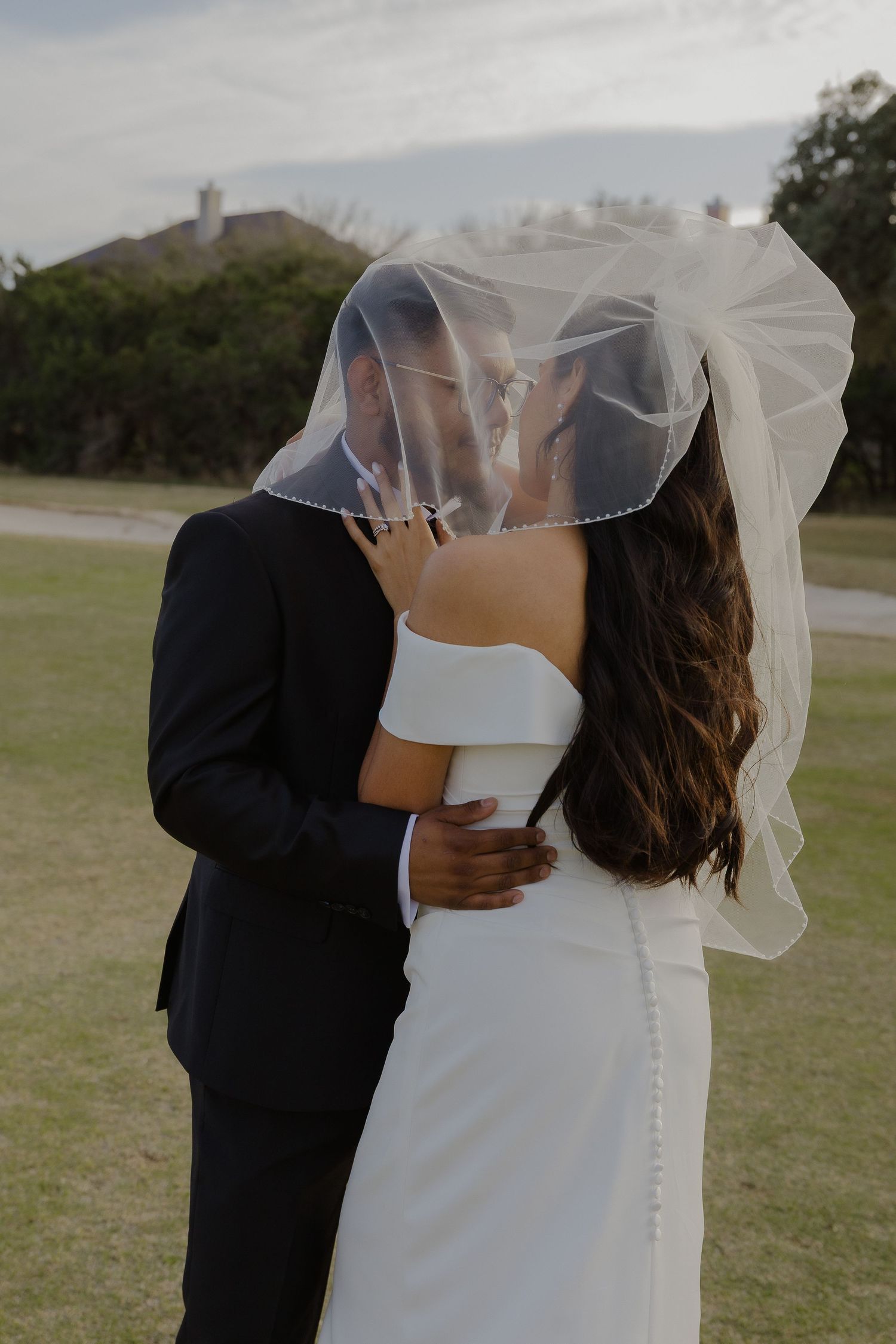 An intimate portrait of newlyweds sharing a romantic moment under a delicate veil.