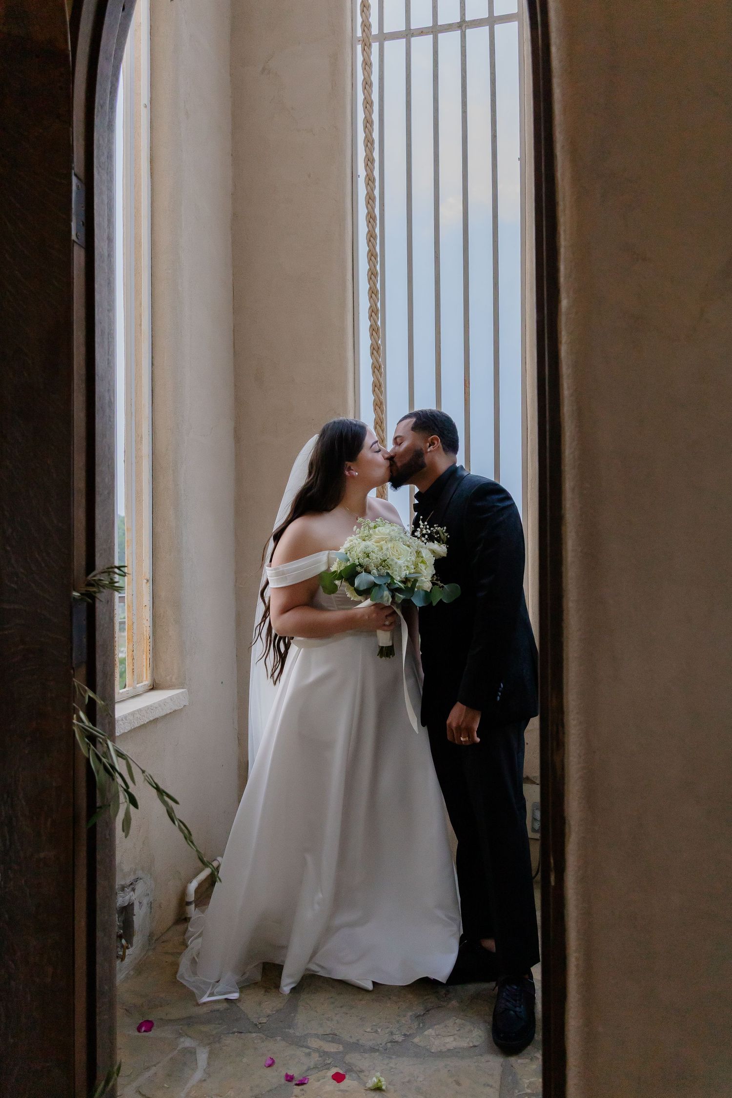 Romantic wedding couple sharing intimate moment by window with white bouquet. Chapel Dulcinea, Austin, Texas.