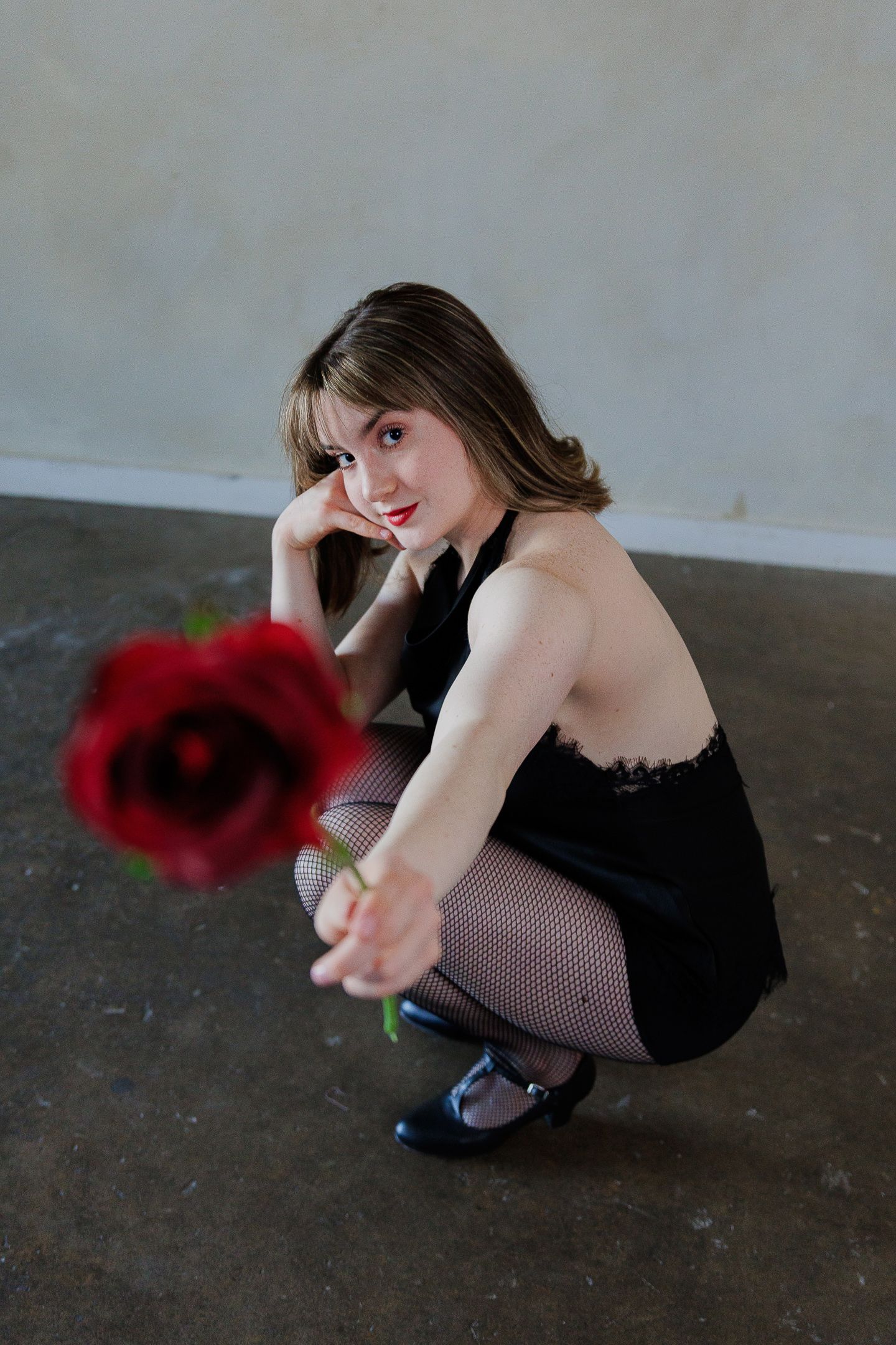 Artistic photo series showing a person in black dress and fishnet stockings posing with red props on concrete floor.