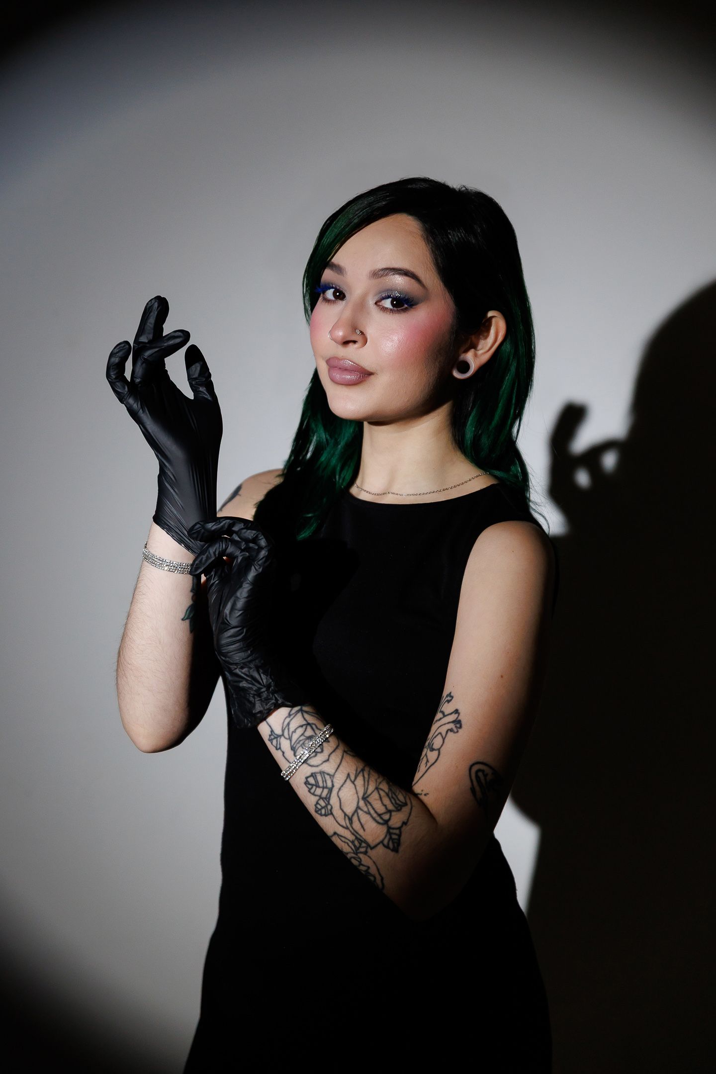 A dramatic fashion portrait series showing a model in black gloves and dress posing against a dark background with tattoos.