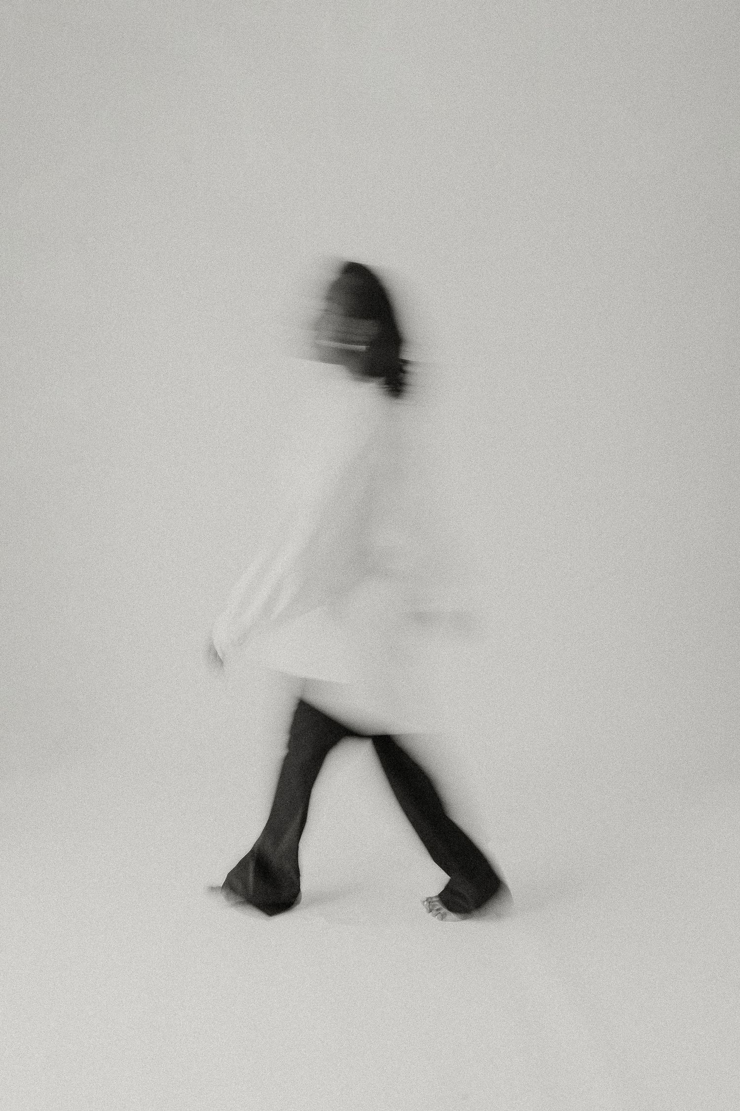 Blurred motion portrait of a person in white dress and black stockings.