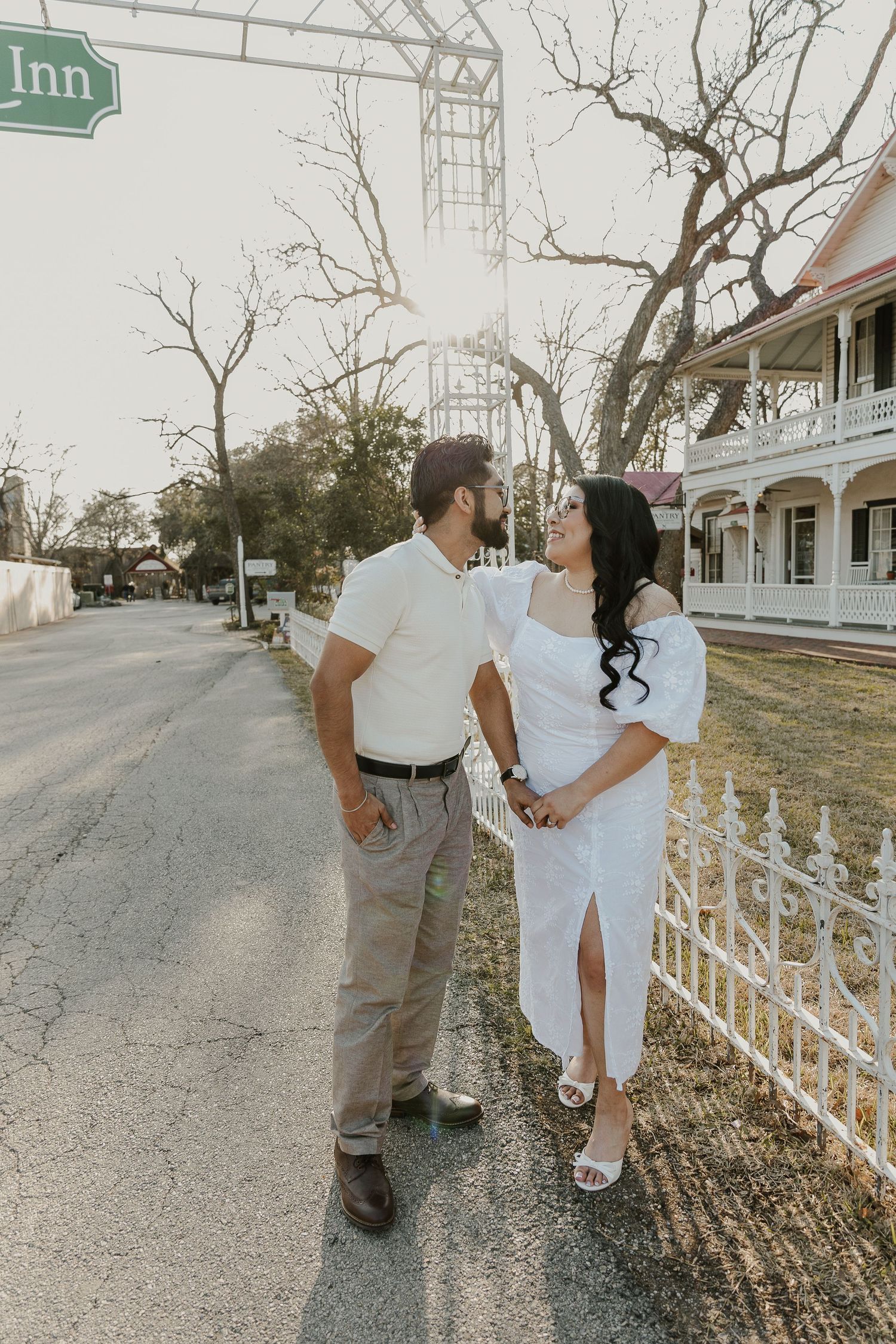 Couple in white outfits walking along street near vintage inn.