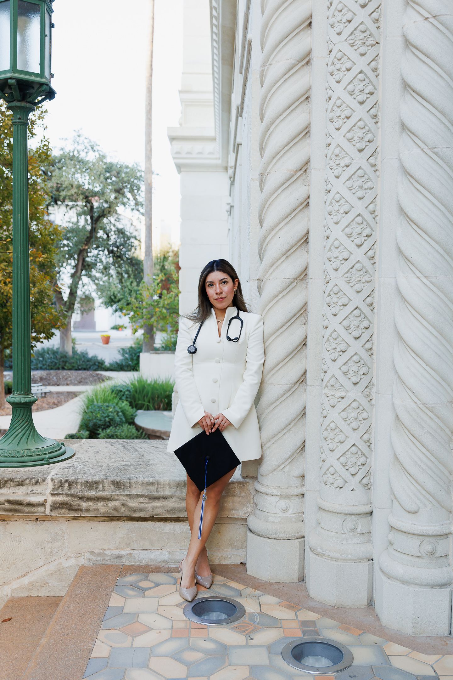 A person in white stands between ornate white stone columns with decorative carvings.