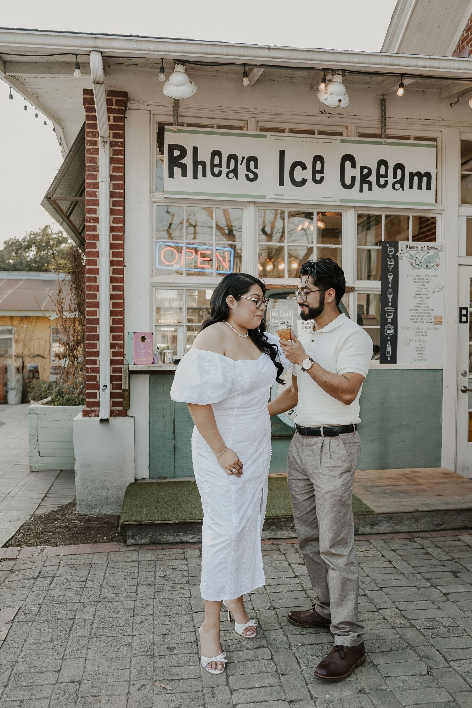 Couple enjoying ice cream outside vintage ice cream shop with brick facade.