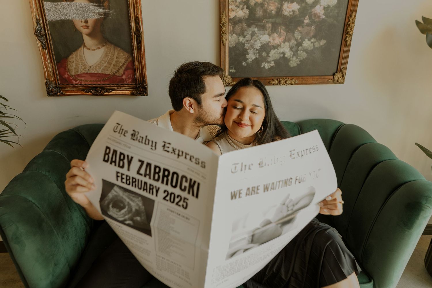 Couple reading a newspaper together on a green velvet couch.