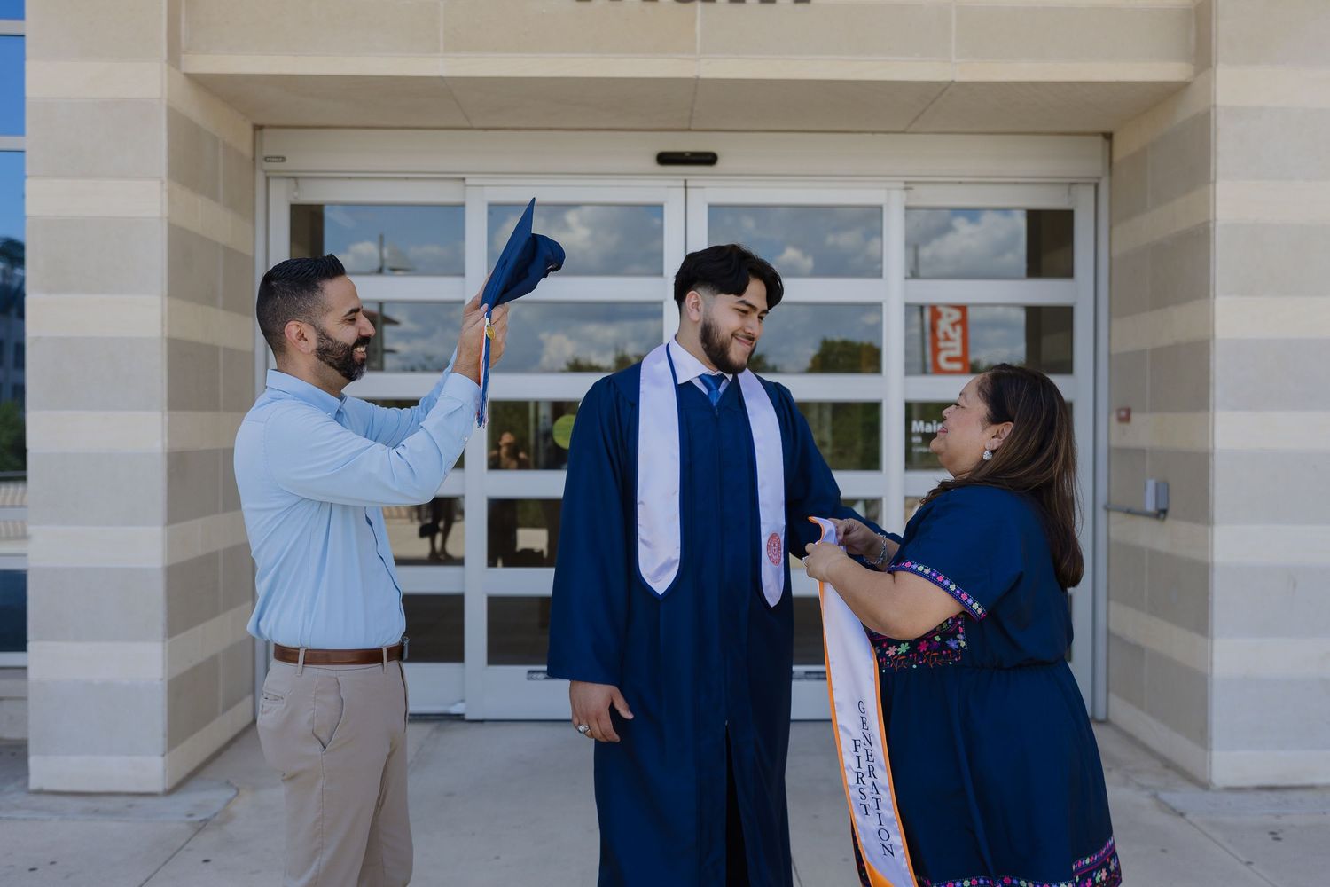 Wedding party members in navy and light blue attire share joyful moments outside a building entrance.