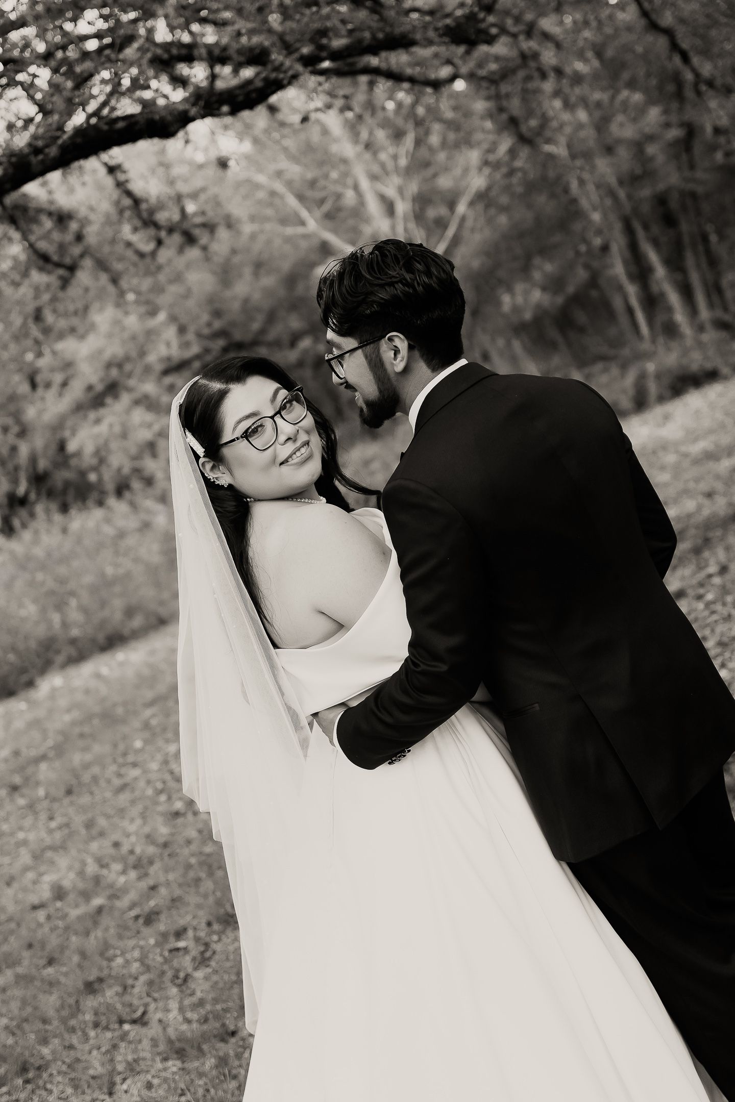 A romantic black and white photo sequence of a bride and groom sharing tender kisses in a natural outdoor setting.