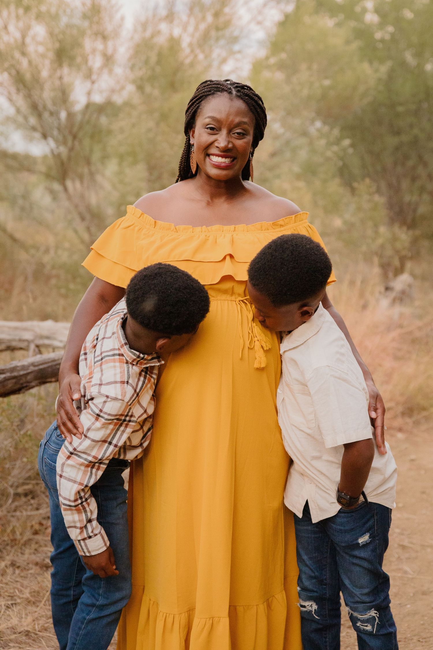 Woman in yellow dress shares joyful moment with two children.