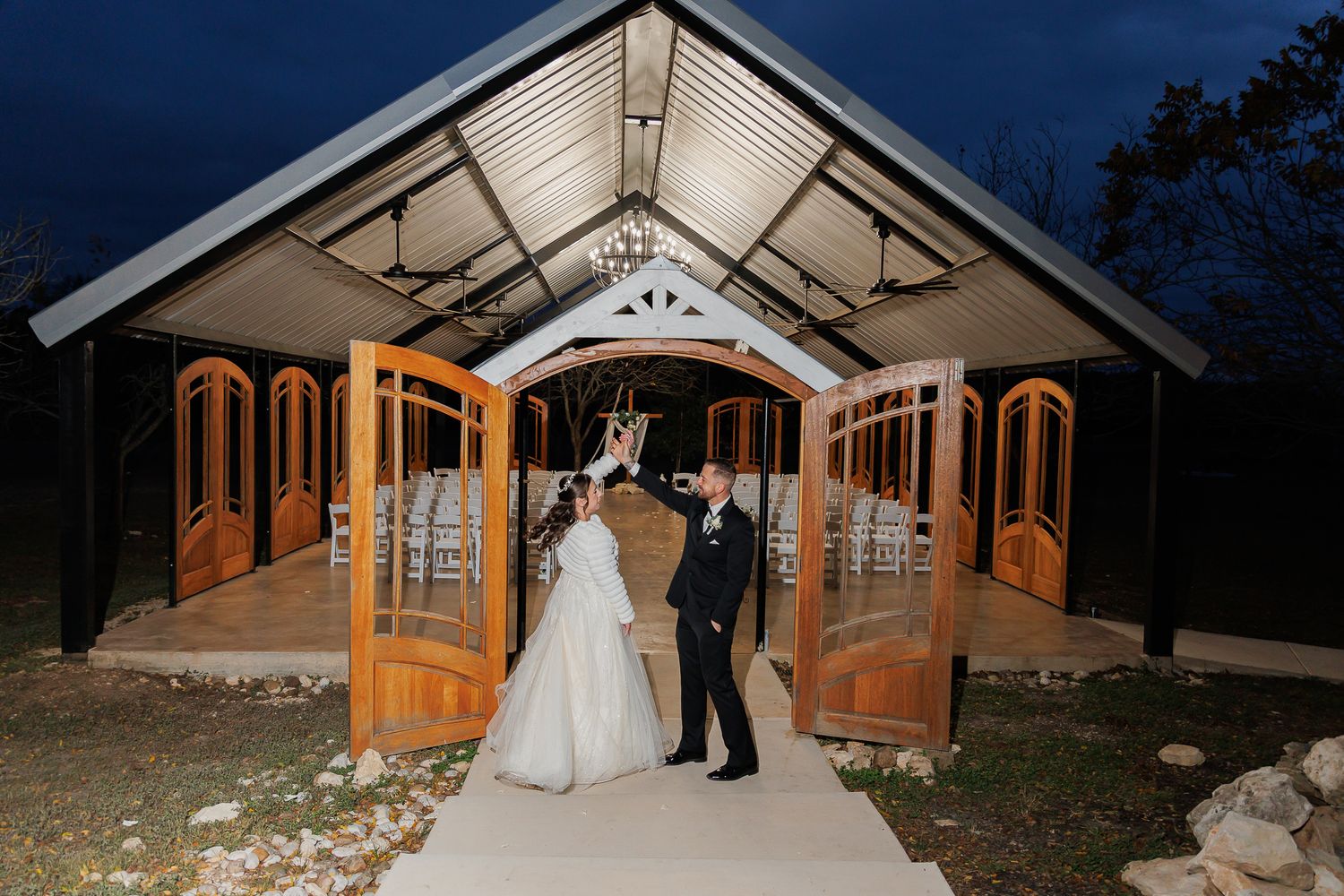 Rustic barn wedding venue decorated with string lights and elegant white drapery for an evening celebration.