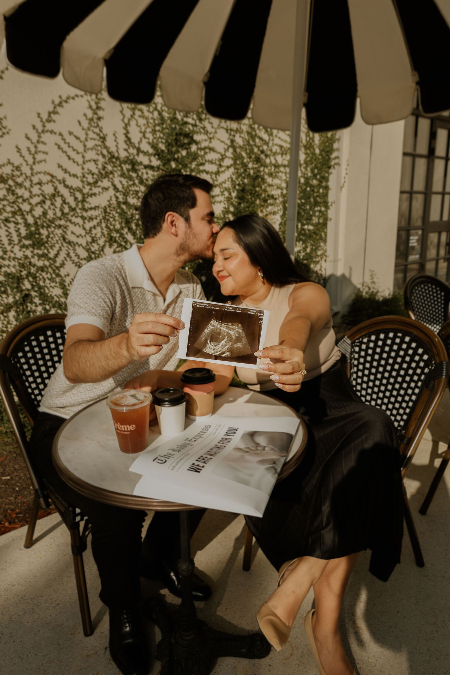 Couple sharing a moment at an outdoor cafe table with striped umbrella.