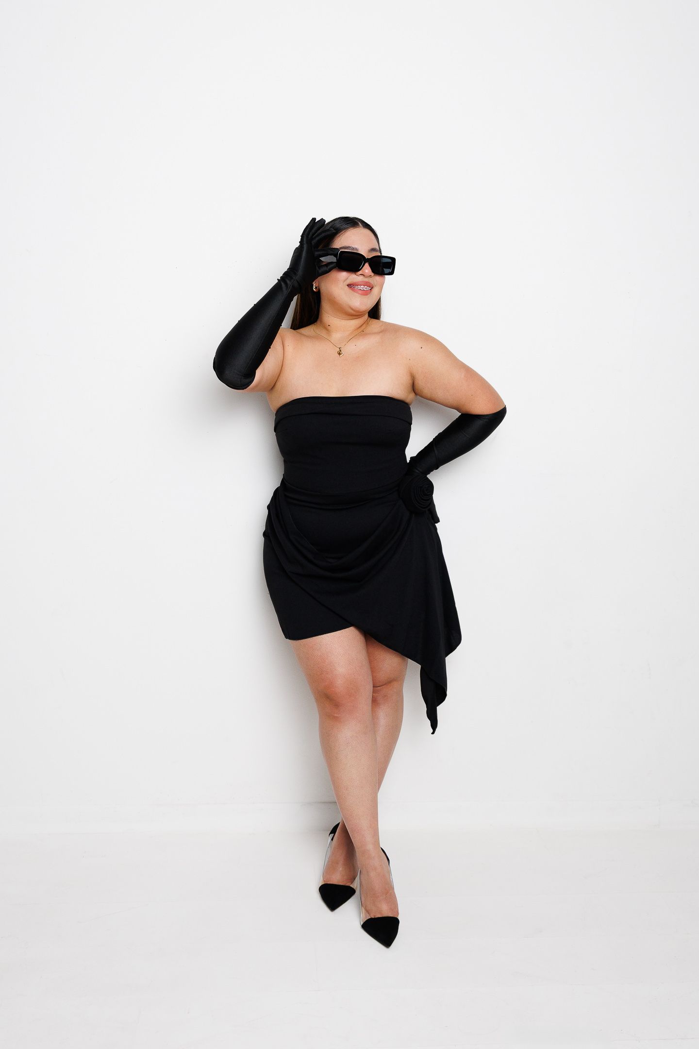 A figure in a black dress strikes dynamic poses against a white background in a four-panel artistic photo series.