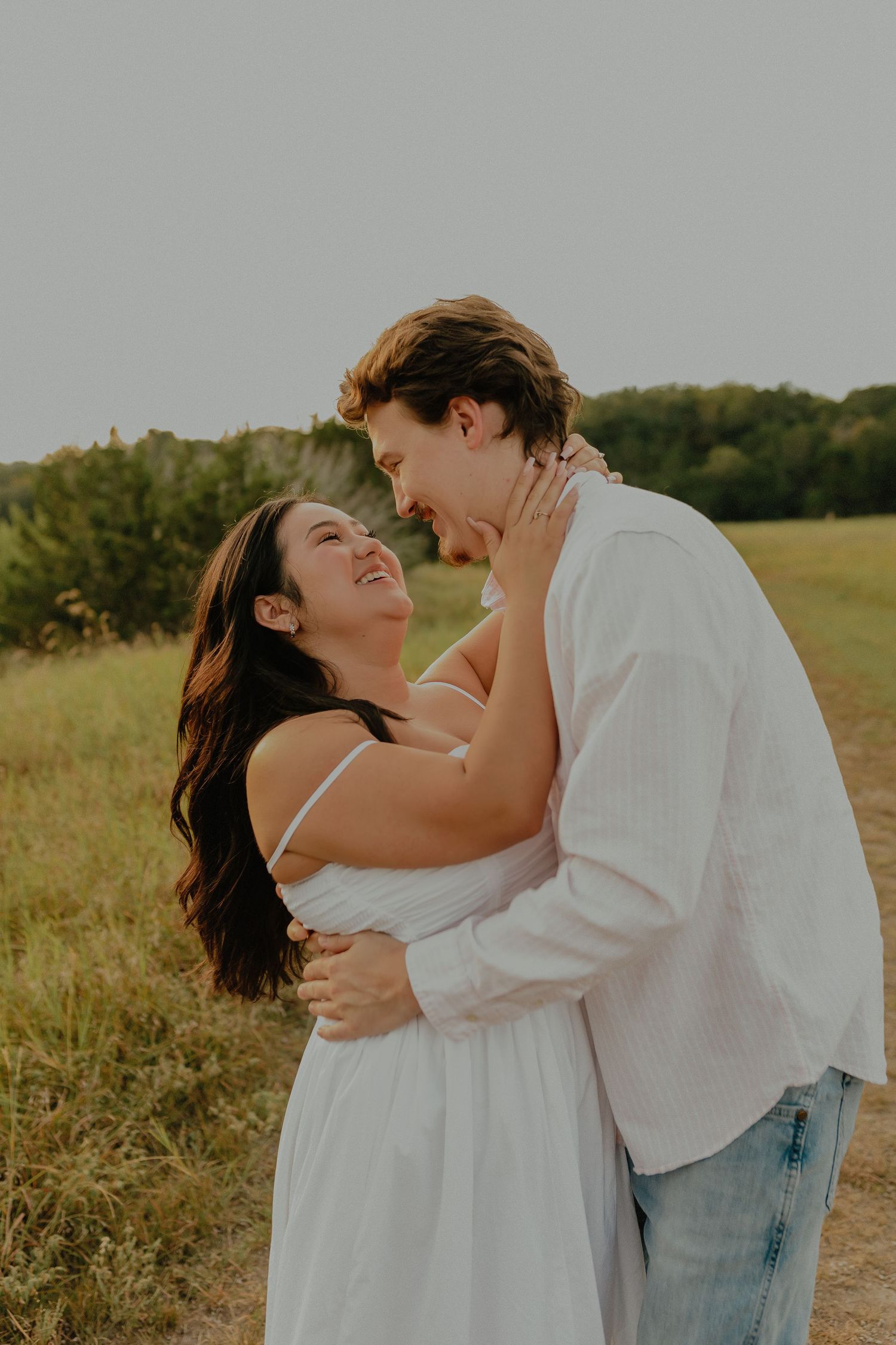 Couple sharing an intimate moment while embracing in a sunny field.