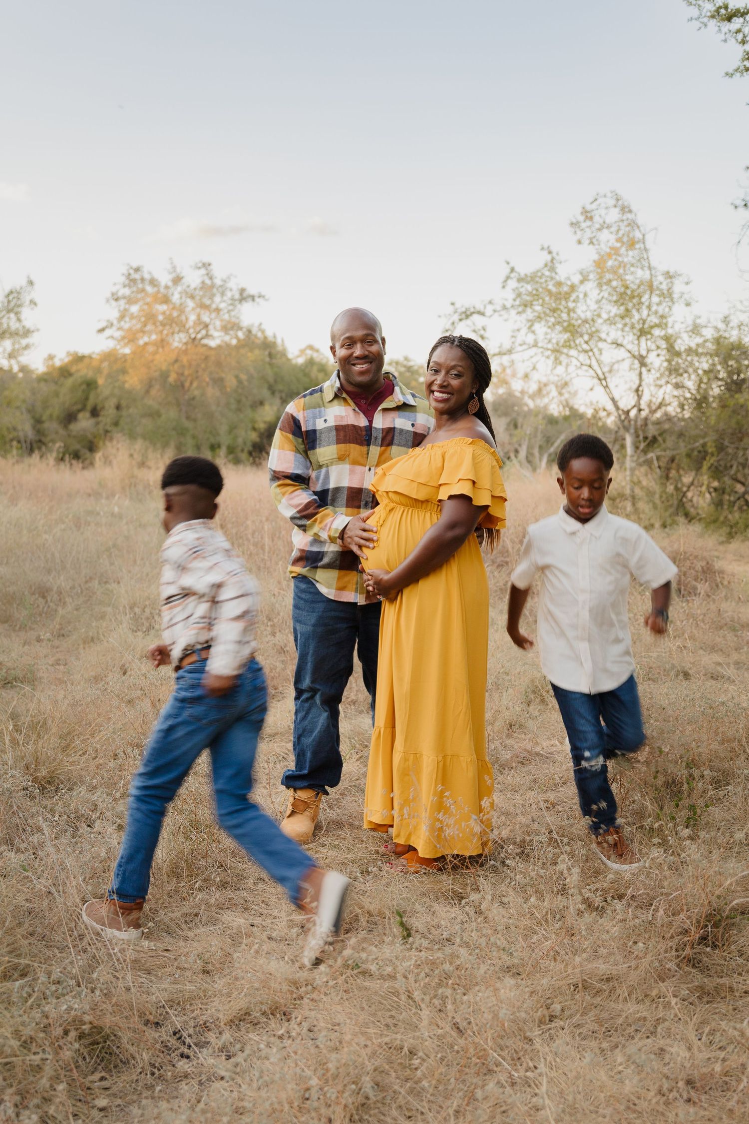 Family enjoying playful moment in outdoor field with children running.