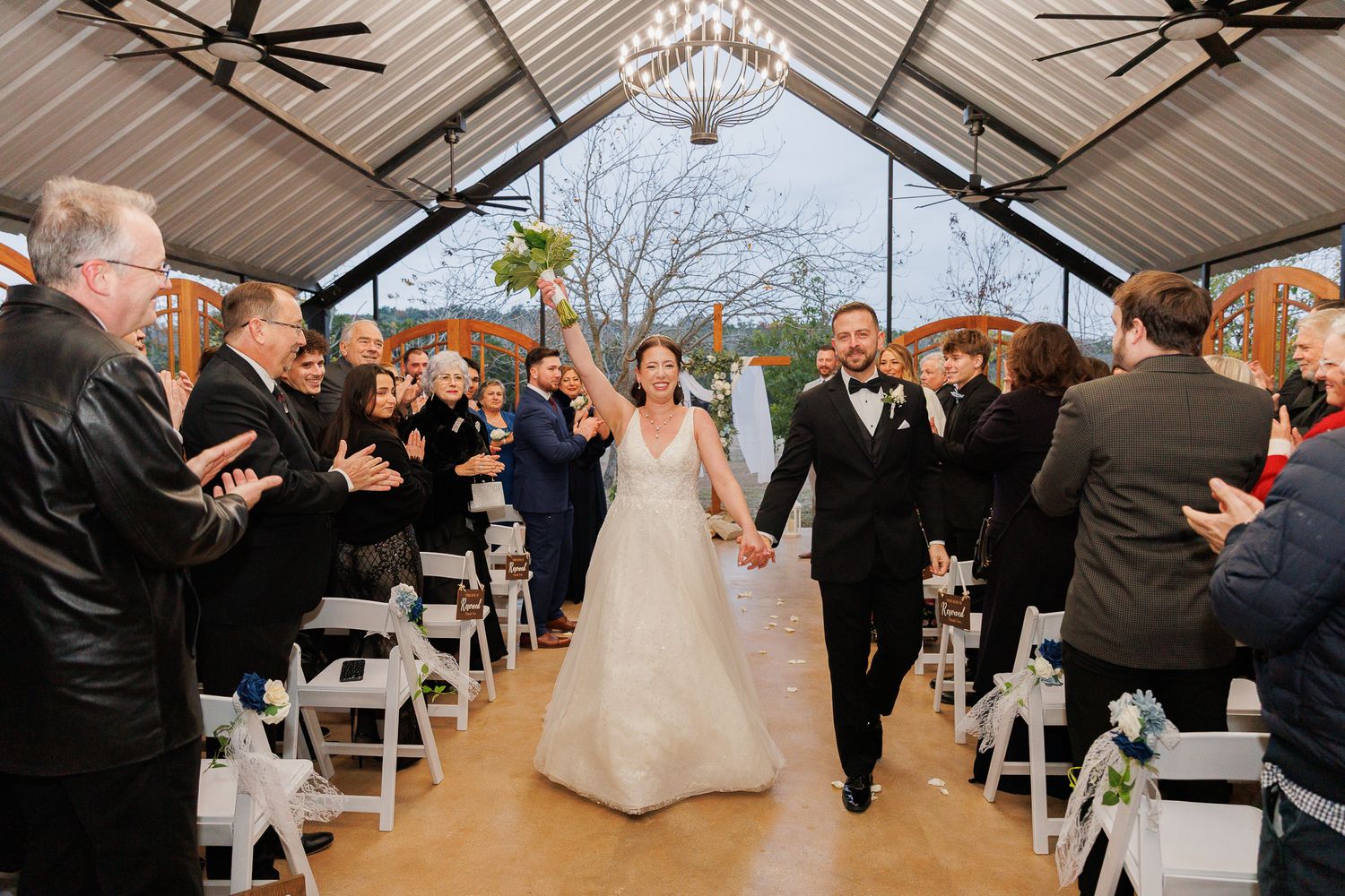 Wedding guests celebrate and dance during a lively reception under a covered outdoor pavilion.