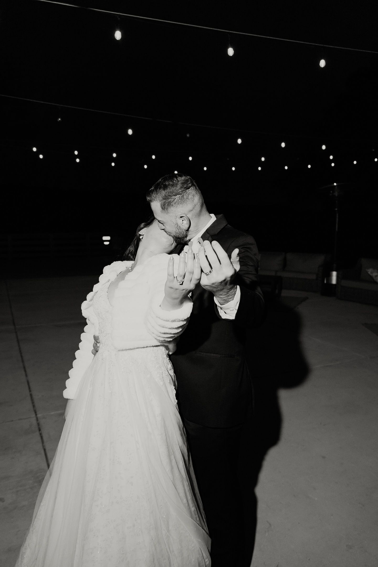 Romantic black and white photos of a couple dancing under string lights at their wedding reception.