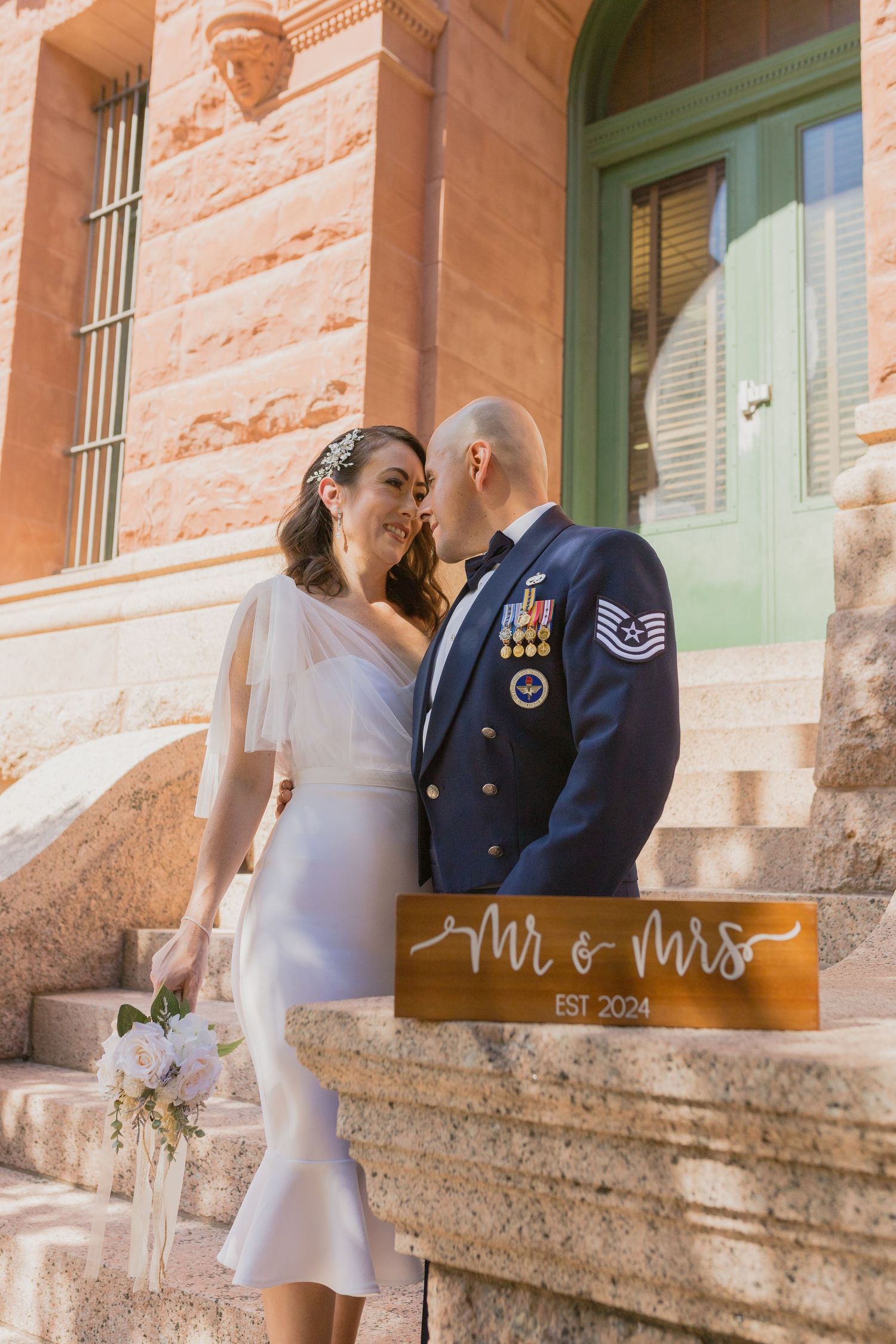 A couple poses with 'Mr & Mrs' sign on historic stone steps.