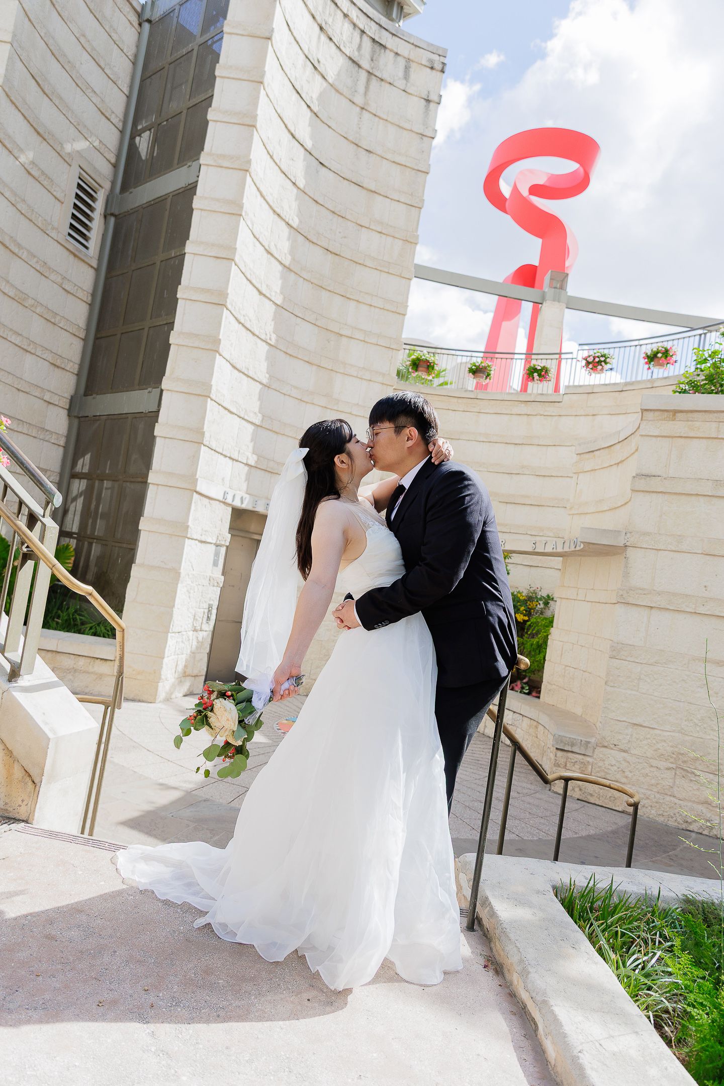A sequence of romantic moments between a couple in white formal attire against a classical stone colonnade.